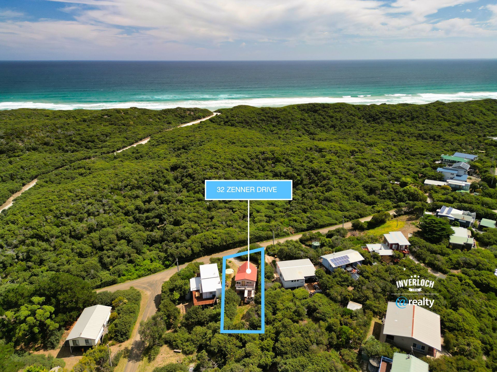 An aerial view of a house surrounded by trees near the ocean