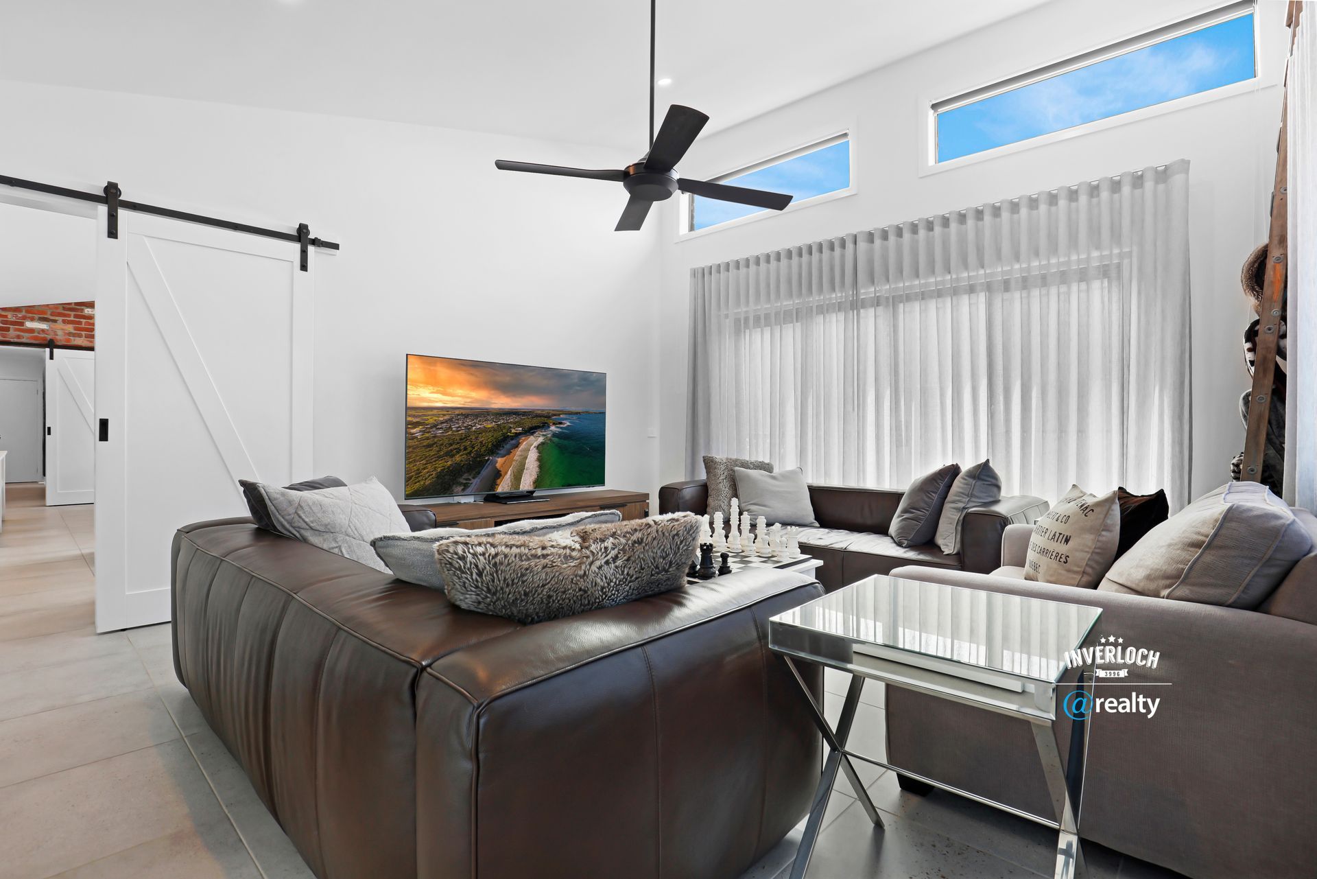 A living room with a couch , table , television and ceiling fan.