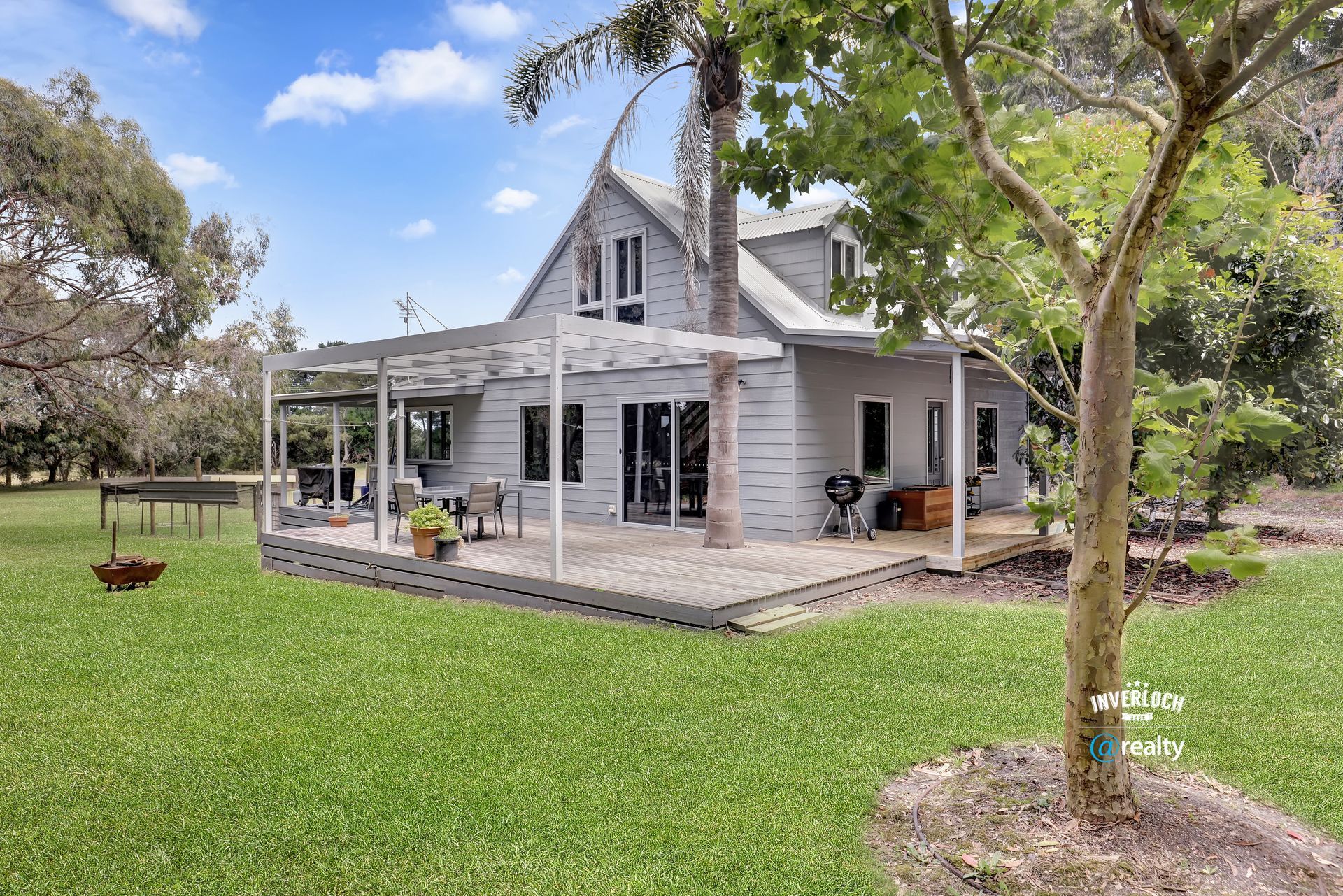 A white house with a porch and a large lawn in front of it.
