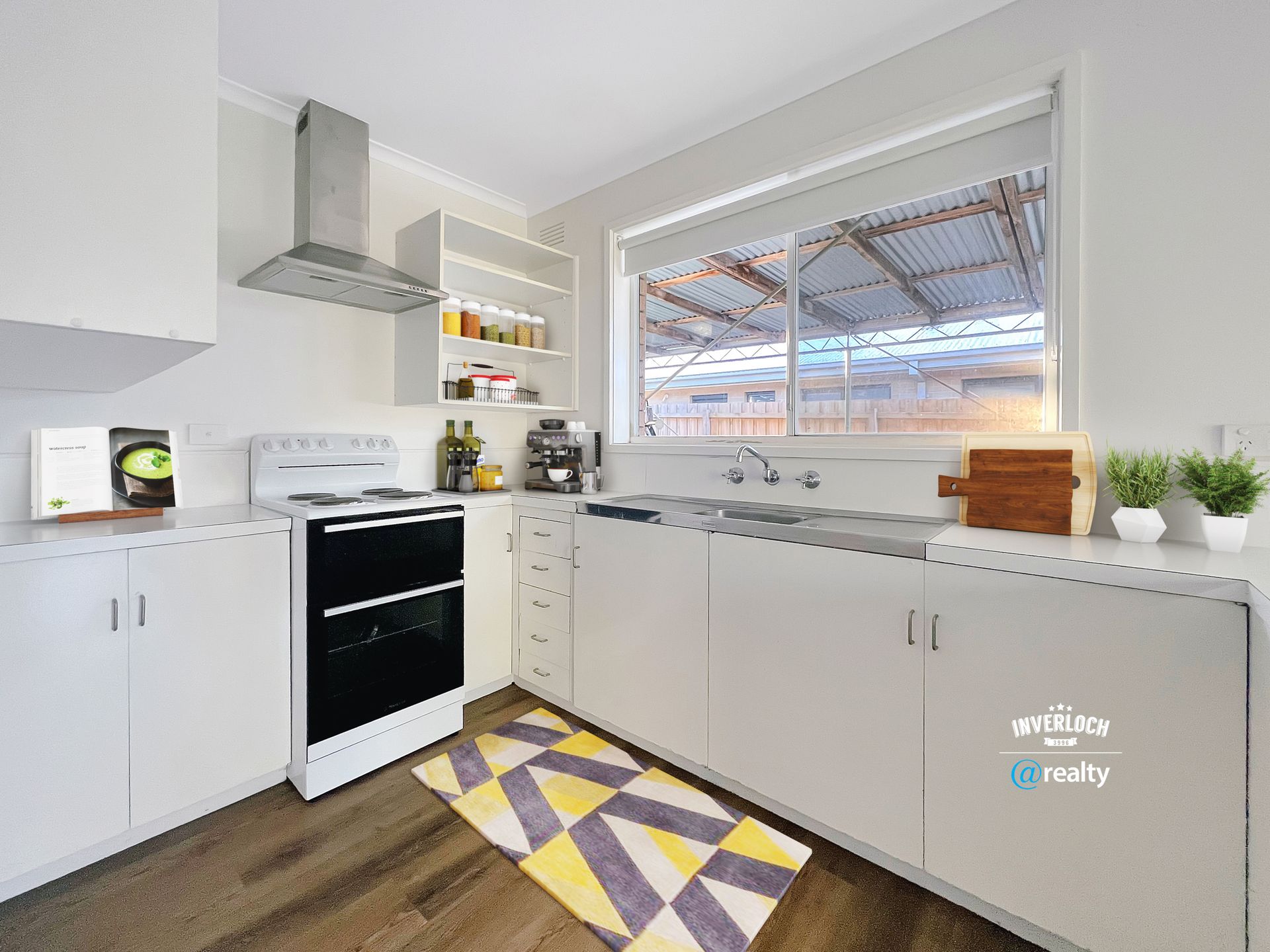 A kitchen with white cabinets , a stove , a sink and a window.