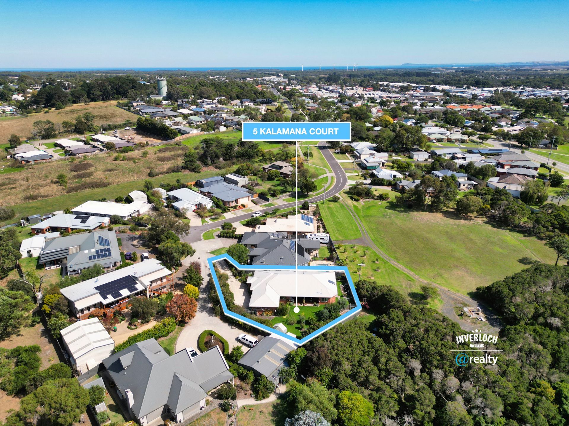 Aerial view of a residential house on a corner lot, highlighted in blue with a street name sign pointing to the property.