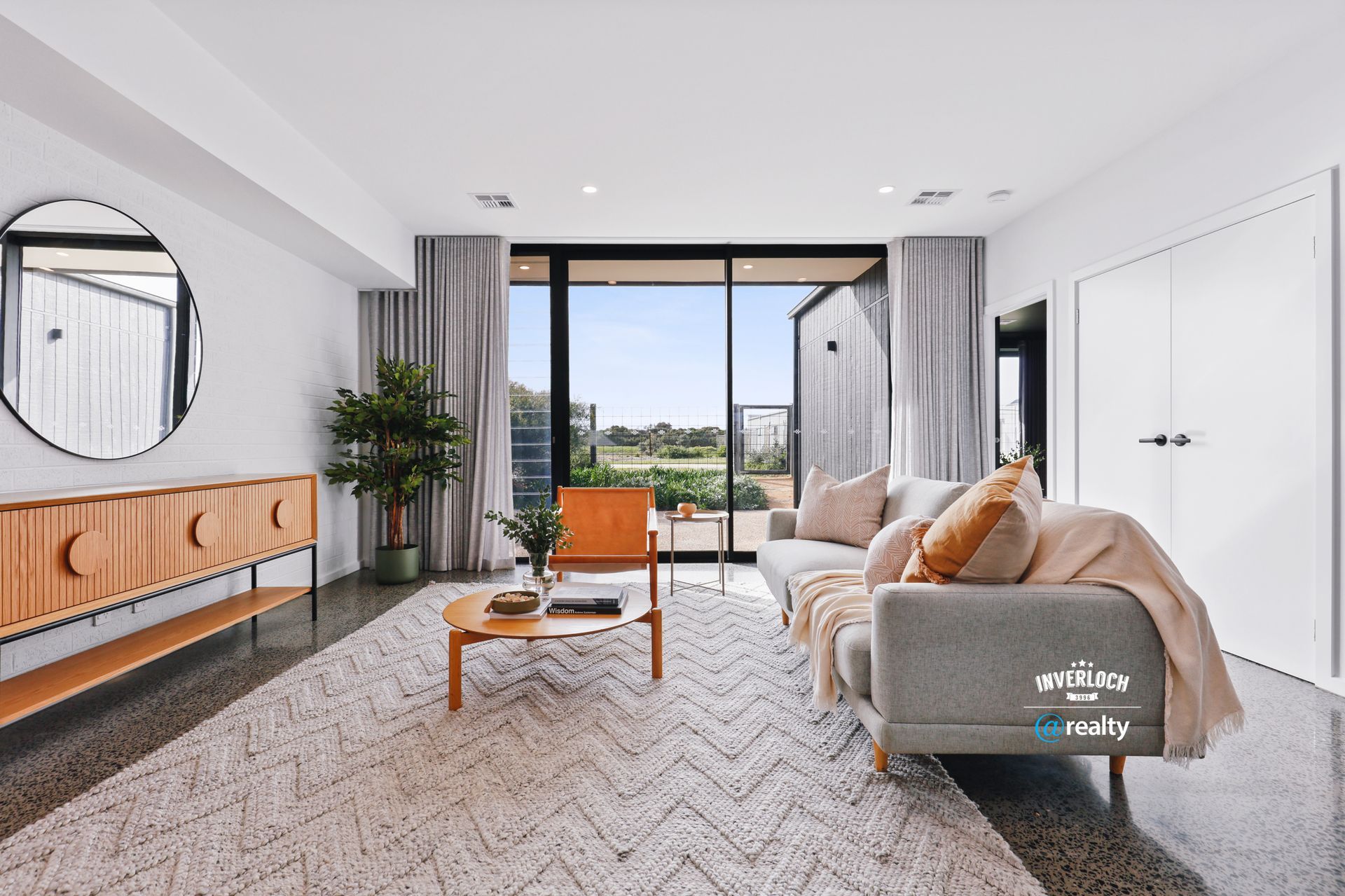 A living room with a couch , chair , table and mirror.