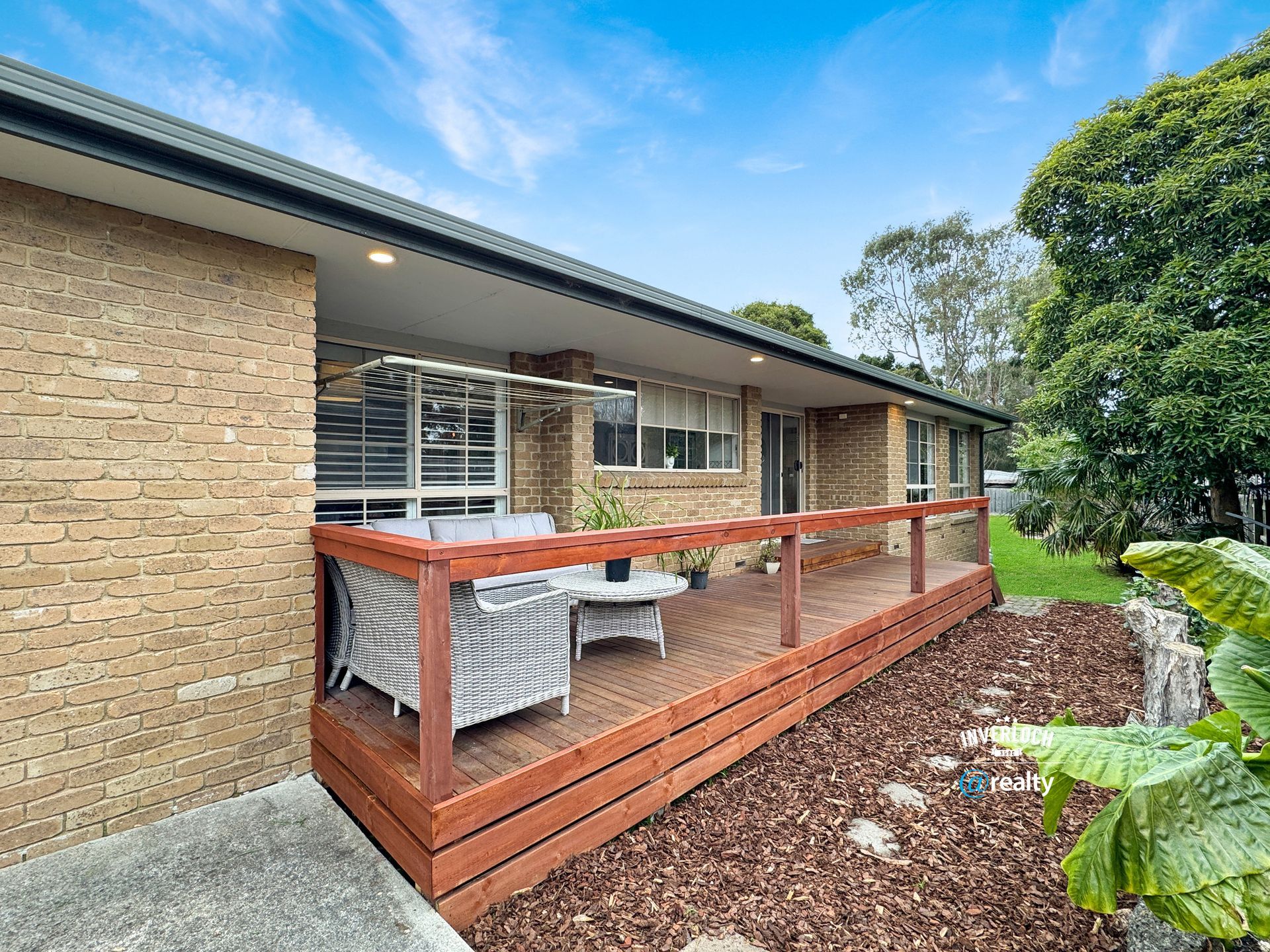 A brick house with a large wooden deck in front of it.