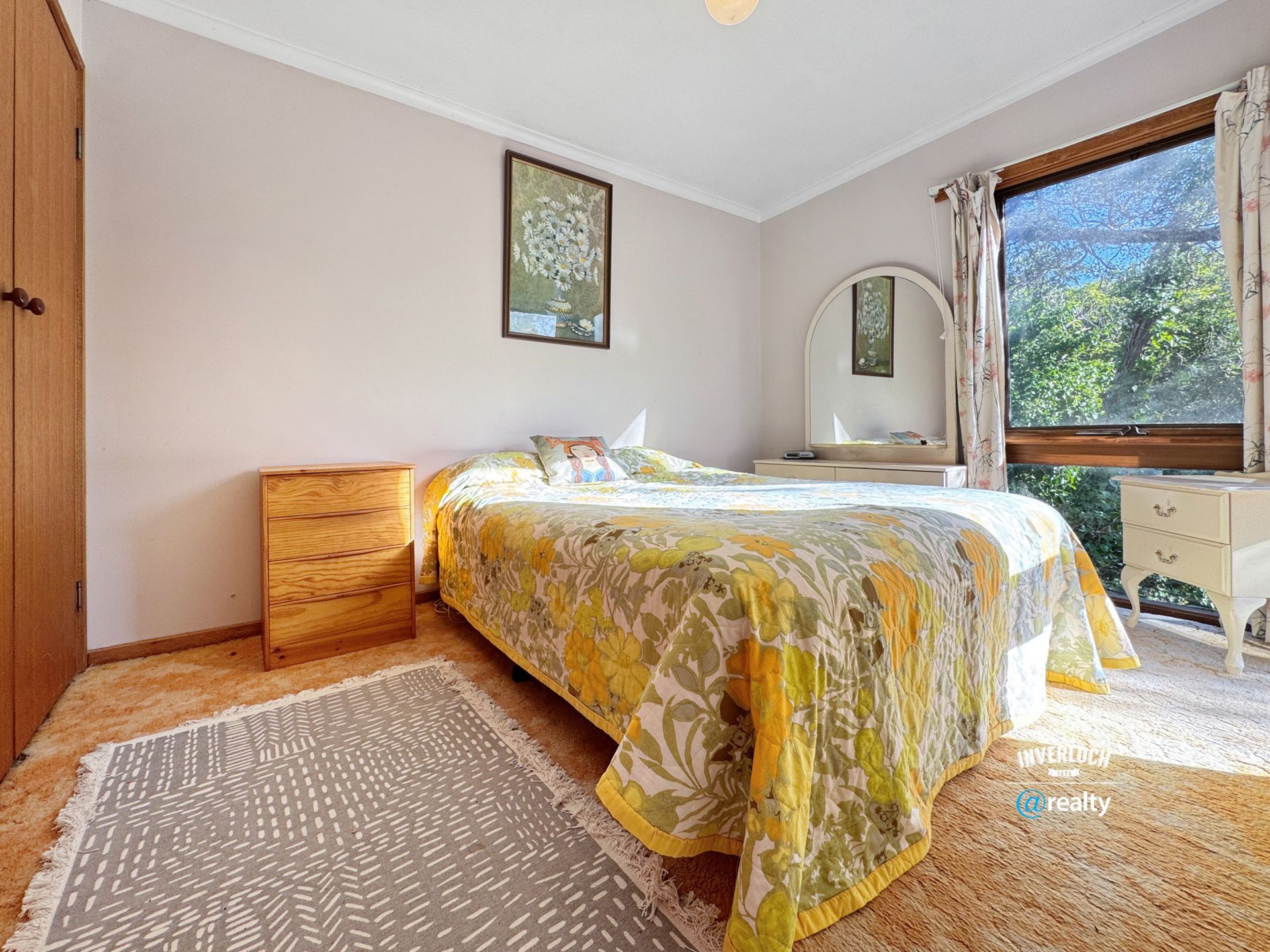 A bedroom with a bed , nightstand , dresser and window.