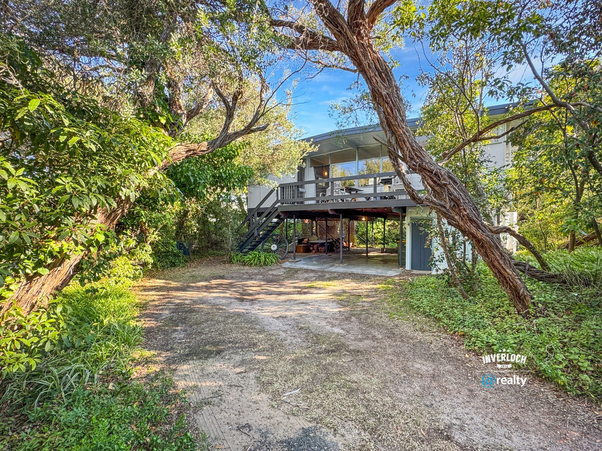 A house with a driveway leading to it is surrounded by trees.