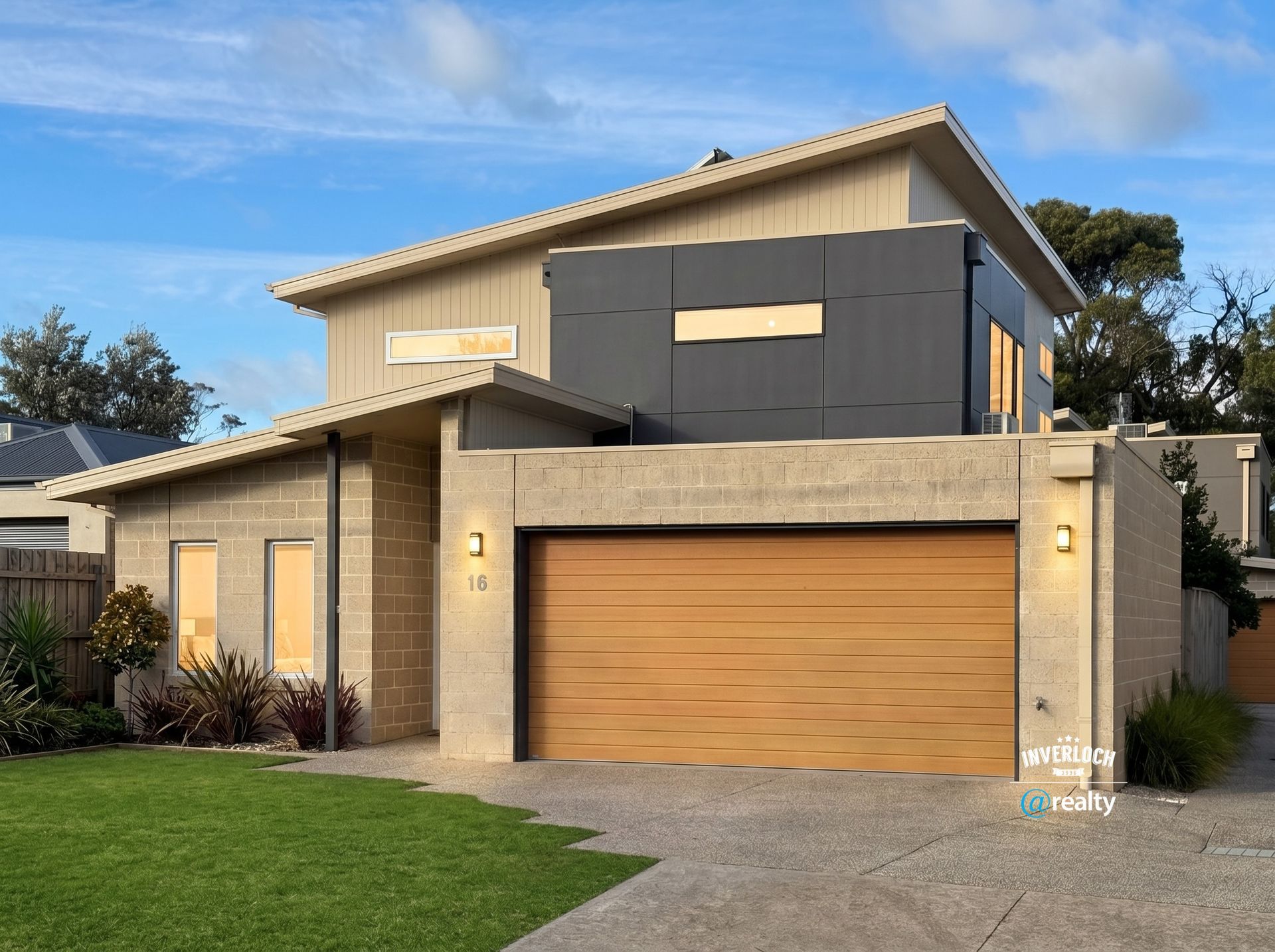 Modern two-story house with beige and gray exterior, double garage, and a manicured front lawn under a blue sky