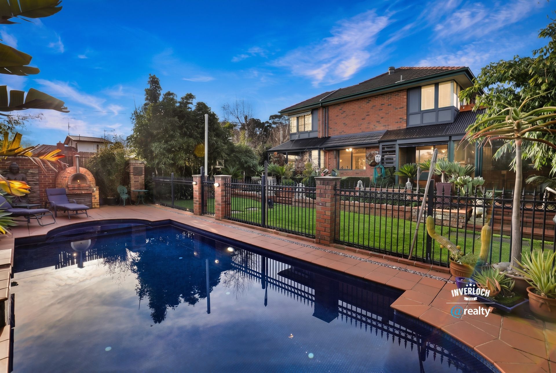 Backyard with a swimming pool reflecting a two-story house under a blue sky