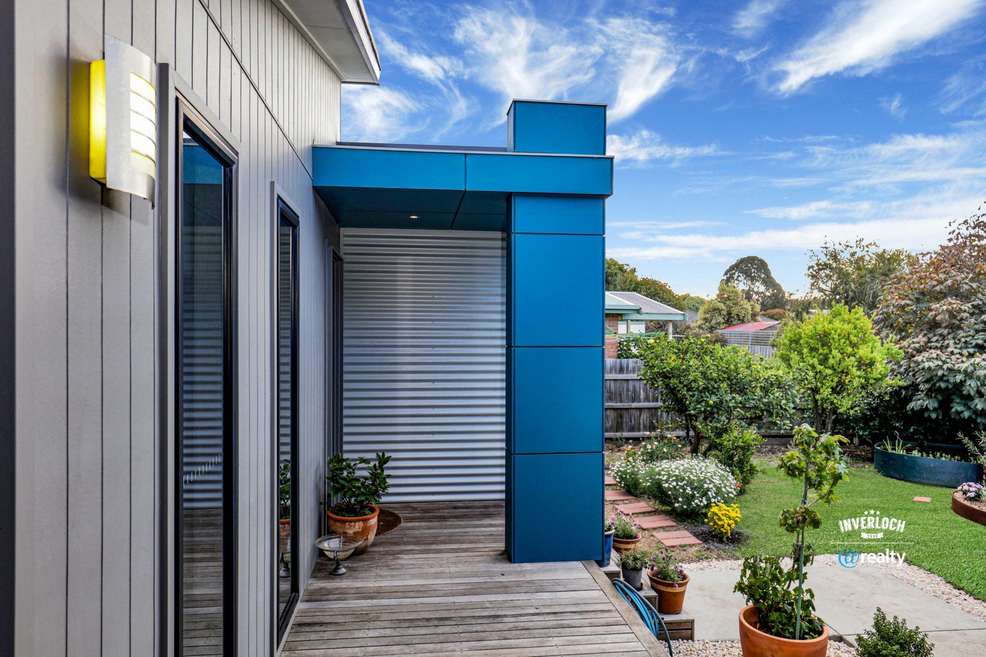A house with a blue garage door and a wooden deck.