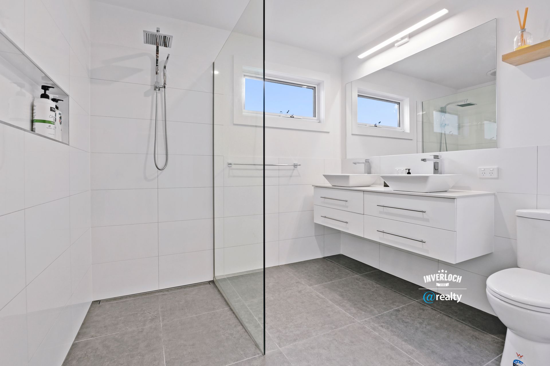 A bathroom with two sinks , a toilet and a walk in shower.