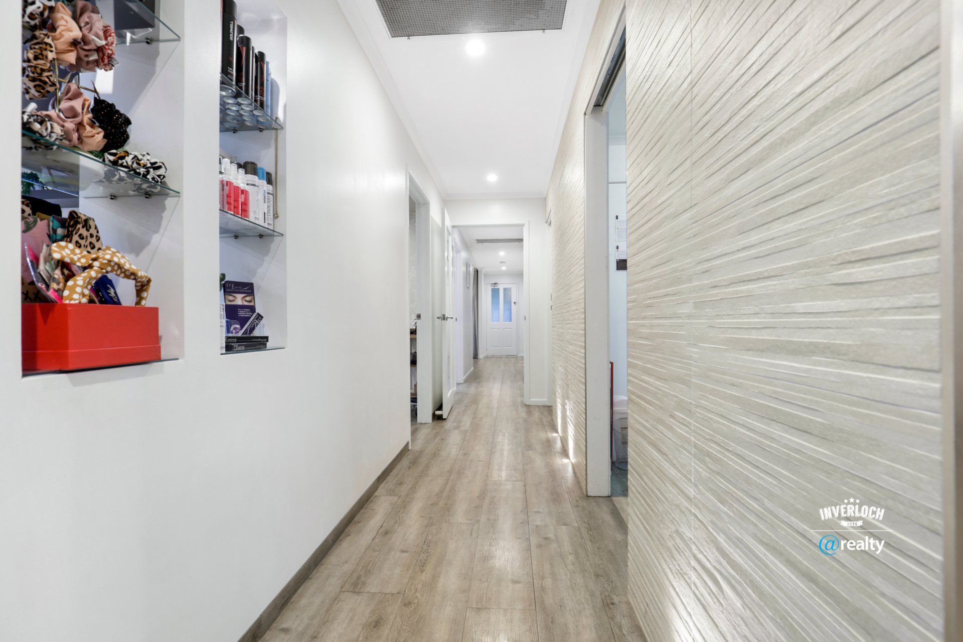 A long hallway with a wooden floor and white walls.