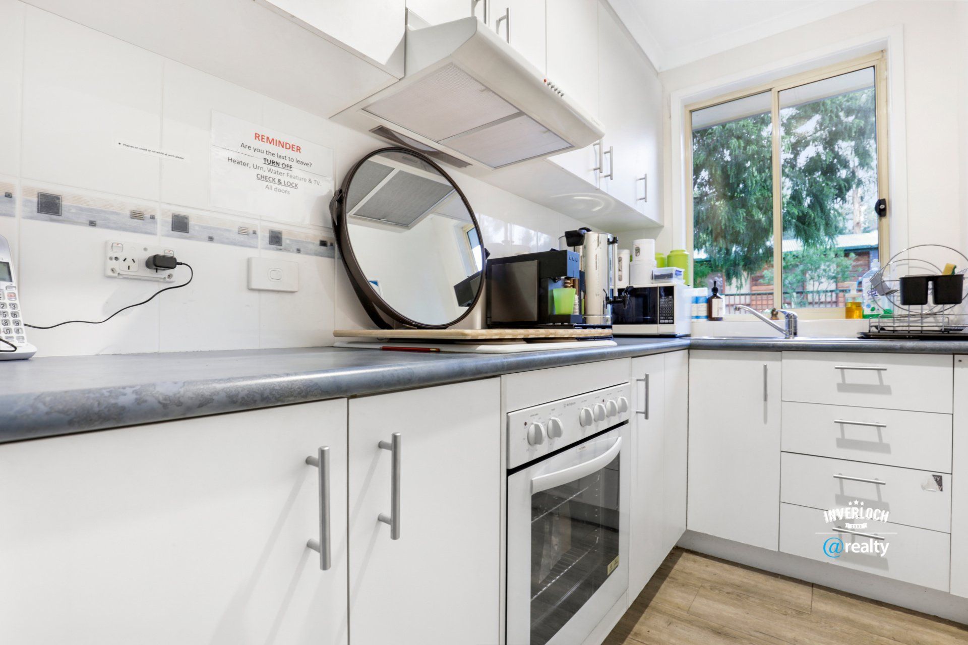 A kitchen with white cabinets , a stove , a microwave , and a mirror.