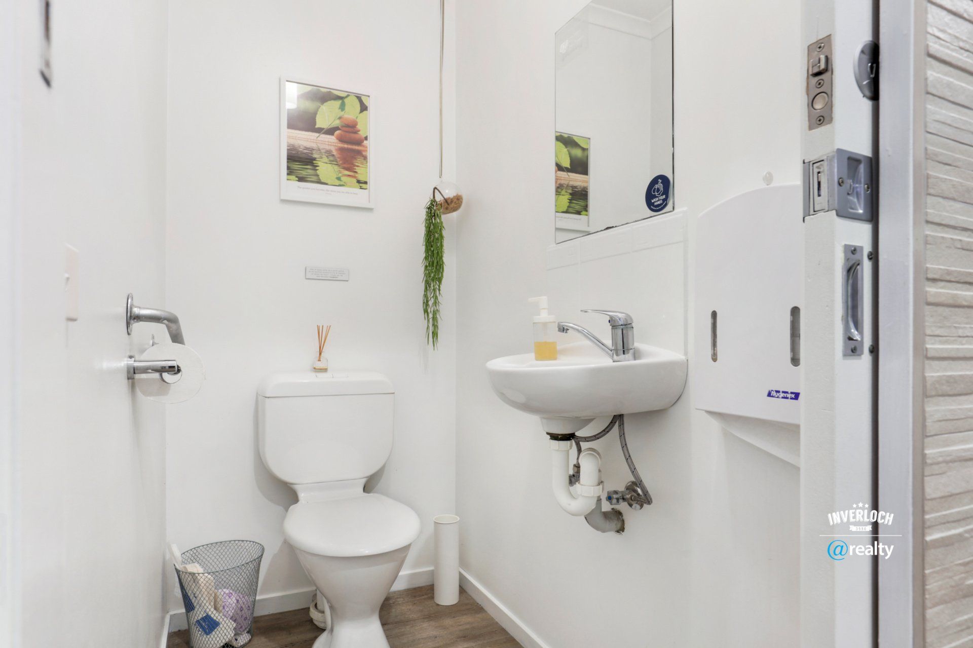 A bathroom with a toilet , sink and mirror.