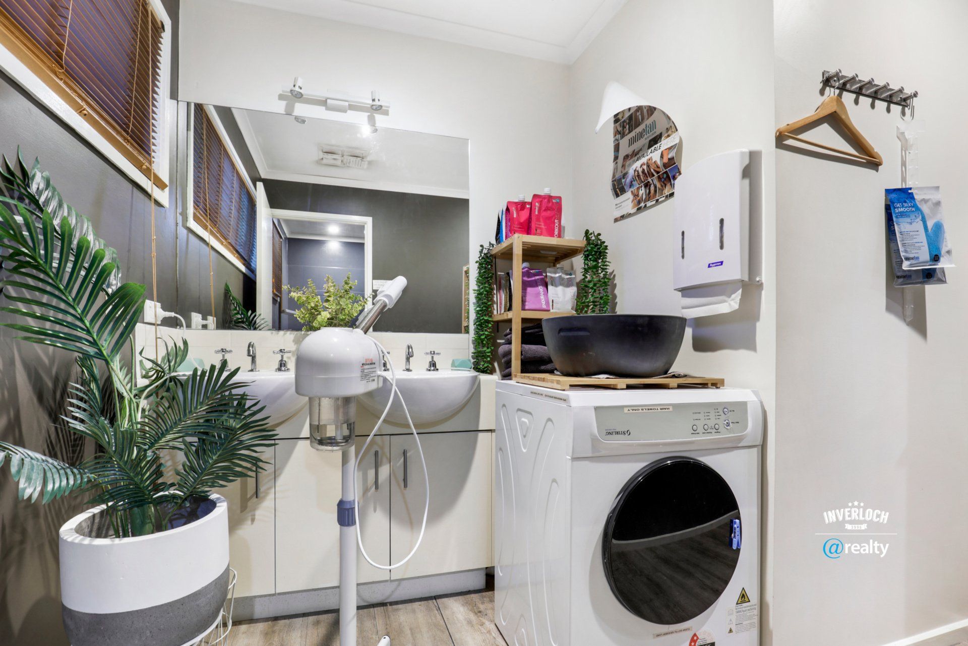 A bathroom with a sink , washing machine , and mirror.