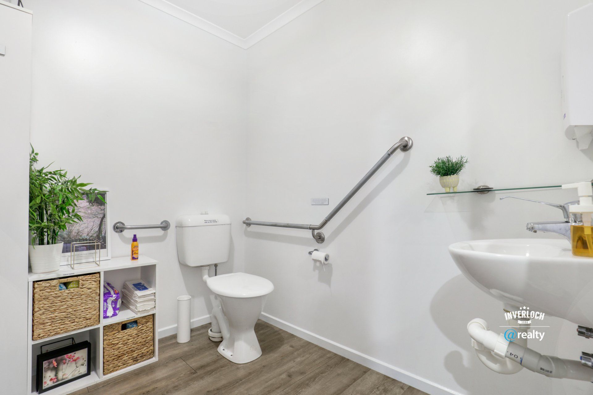A bathroom with a toilet , sink , and shelf.