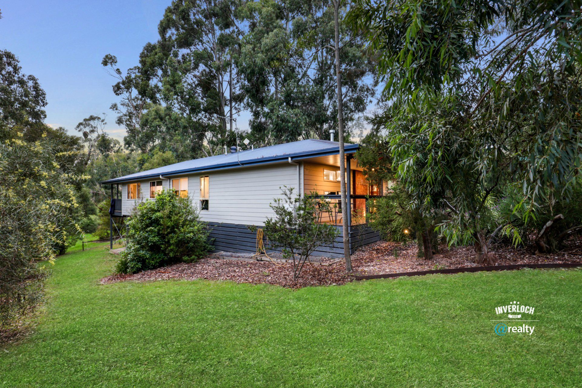 A small house is sitting in the middle of a lush green field surrounded by trees.