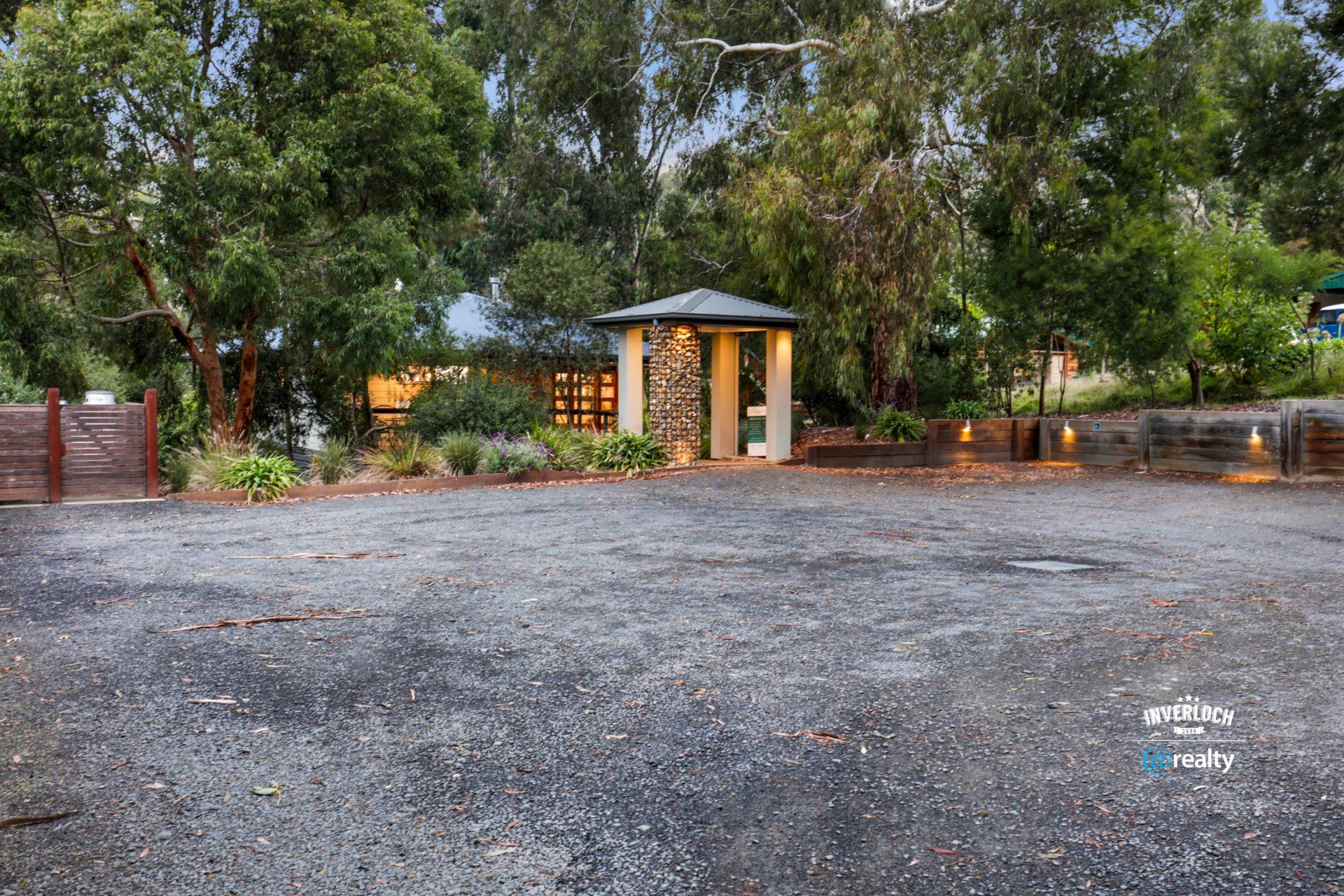 A large empty parking lot in front of a house surrounded by trees.