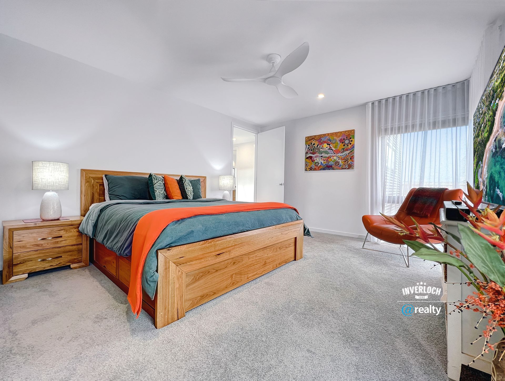 A bedroom with a king size bed , nightstand , chair and ceiling fan.