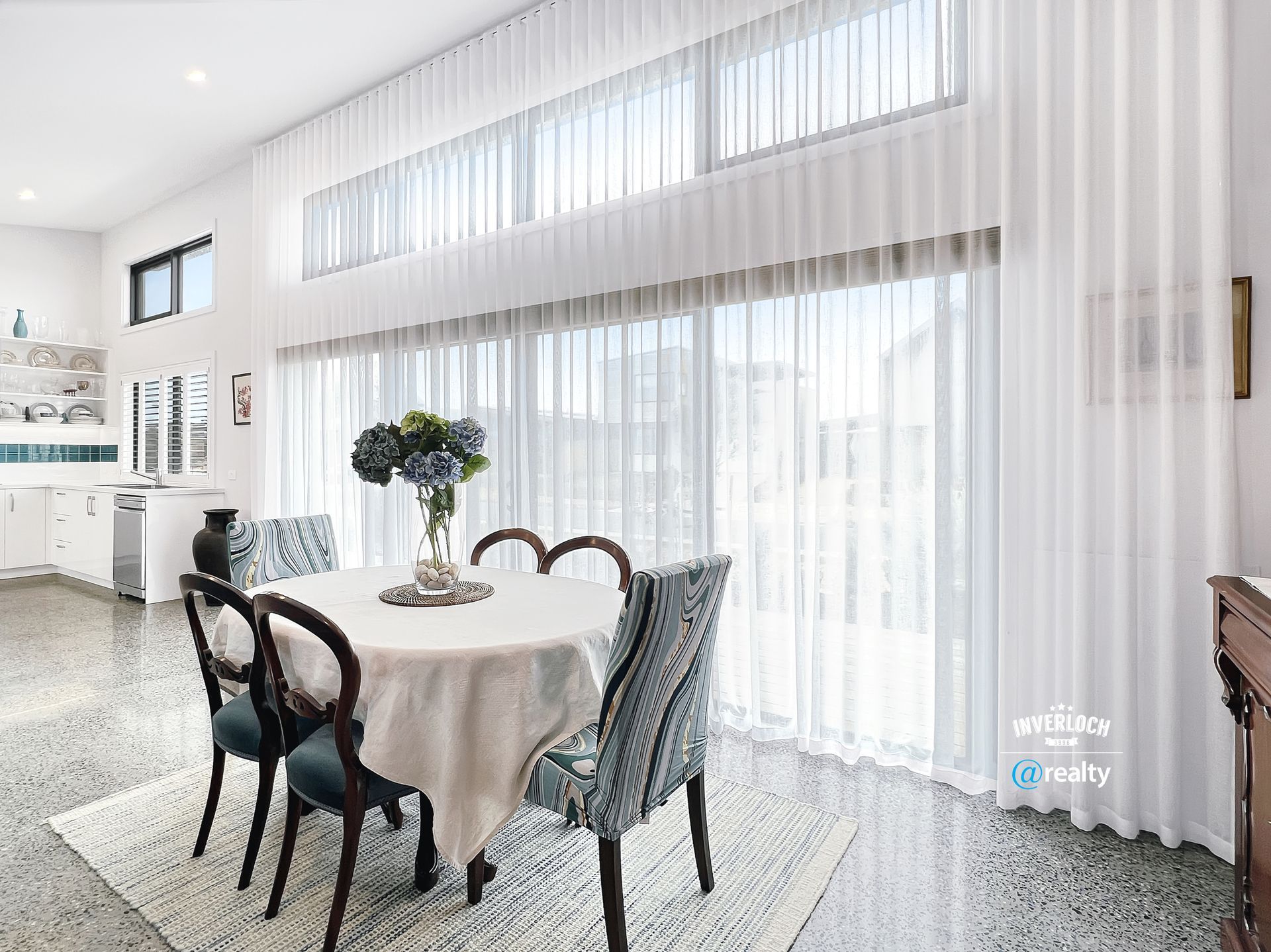 A dining room with a table and chairs and sliding glass doors.