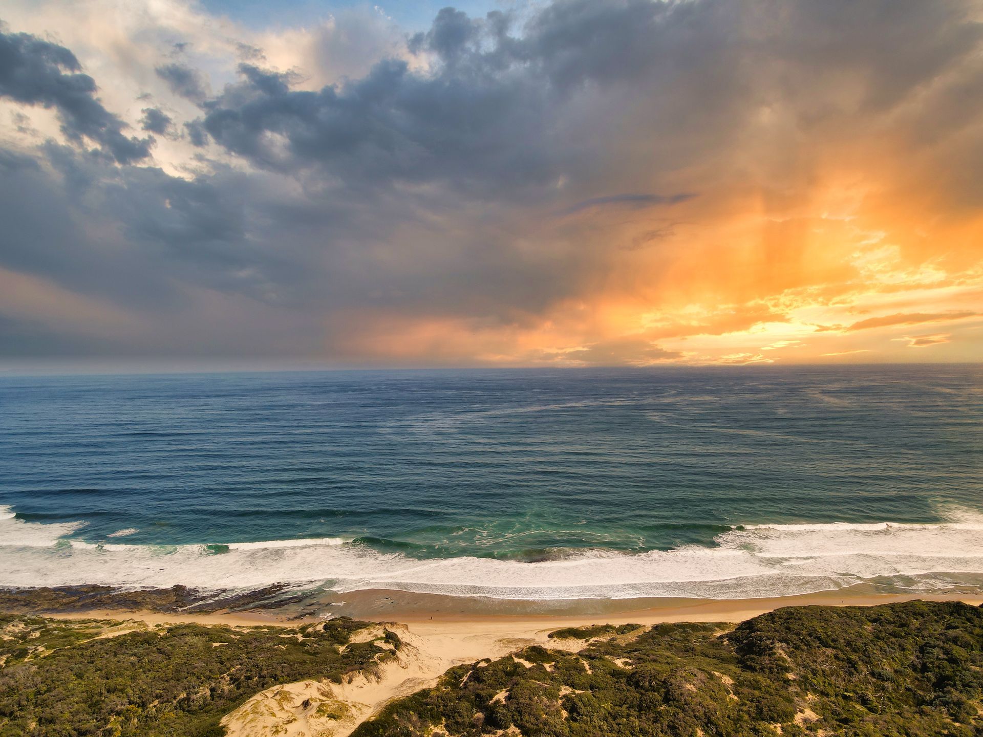 An aerial view of a beach with a sunset in the background.