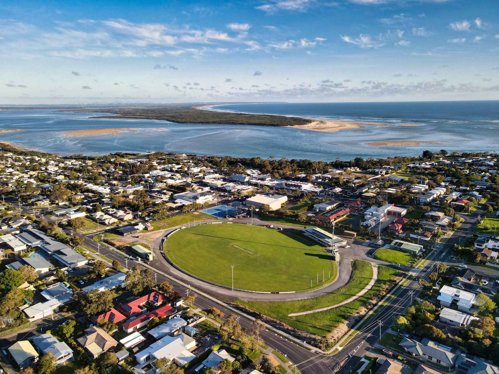 An aerial view of a city with a soccer field and a large body of water in the background.
