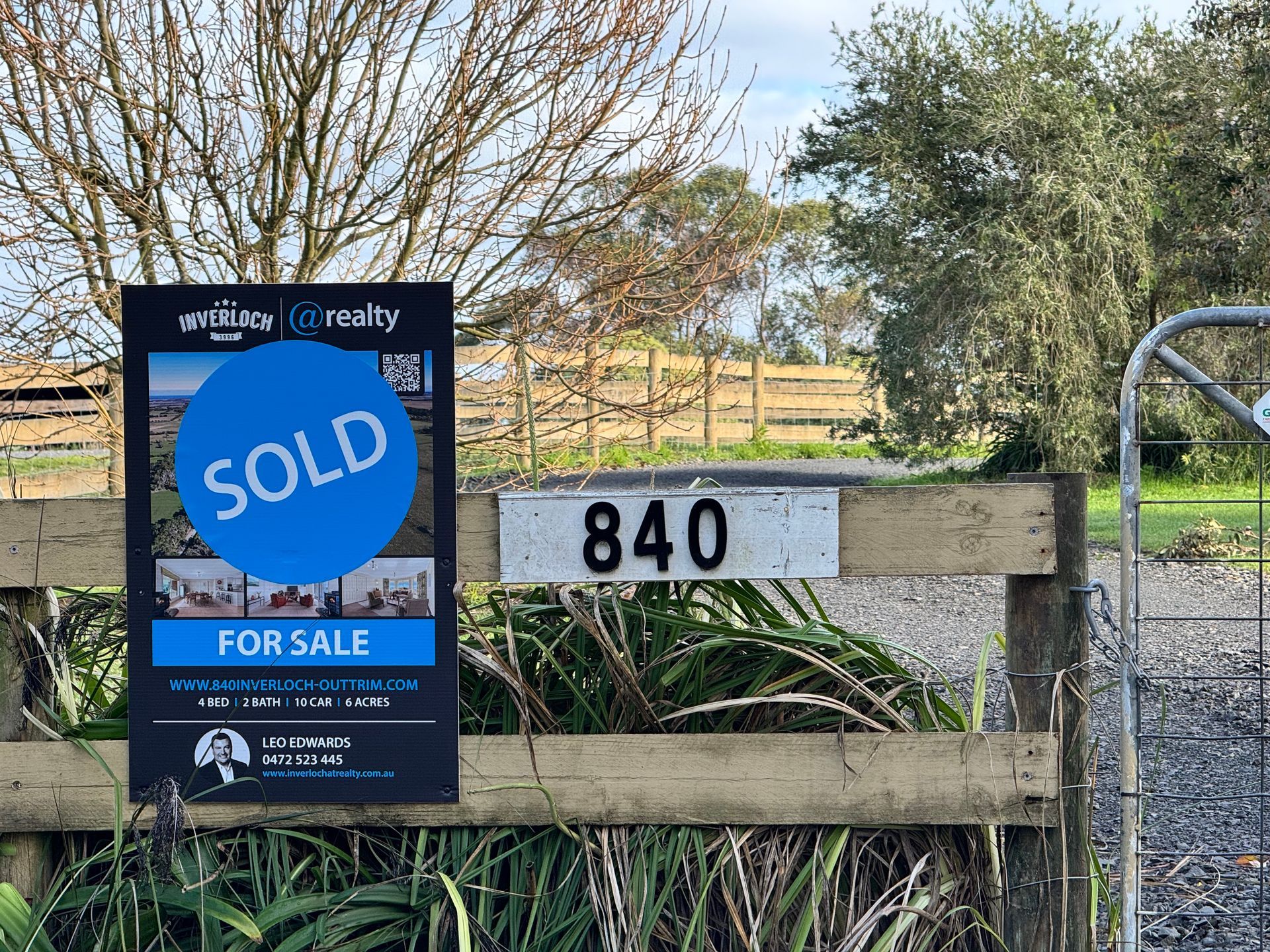 A sold for sale sign is attached to a wooden fence.