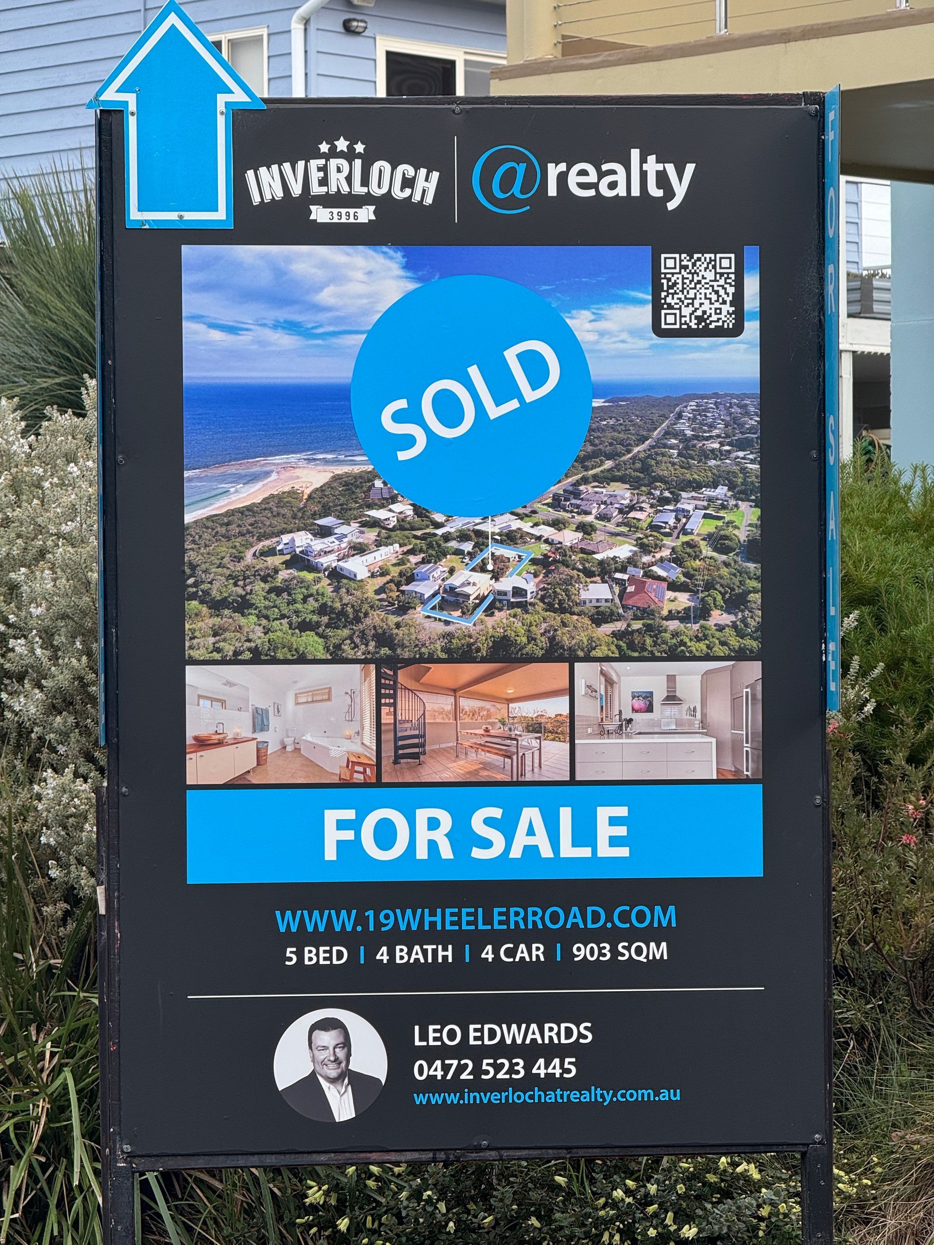 Real estate sign with aerial neighborhood photo, blue SOLD circle, and FOR SALE banner for The Real Est8 Realty.