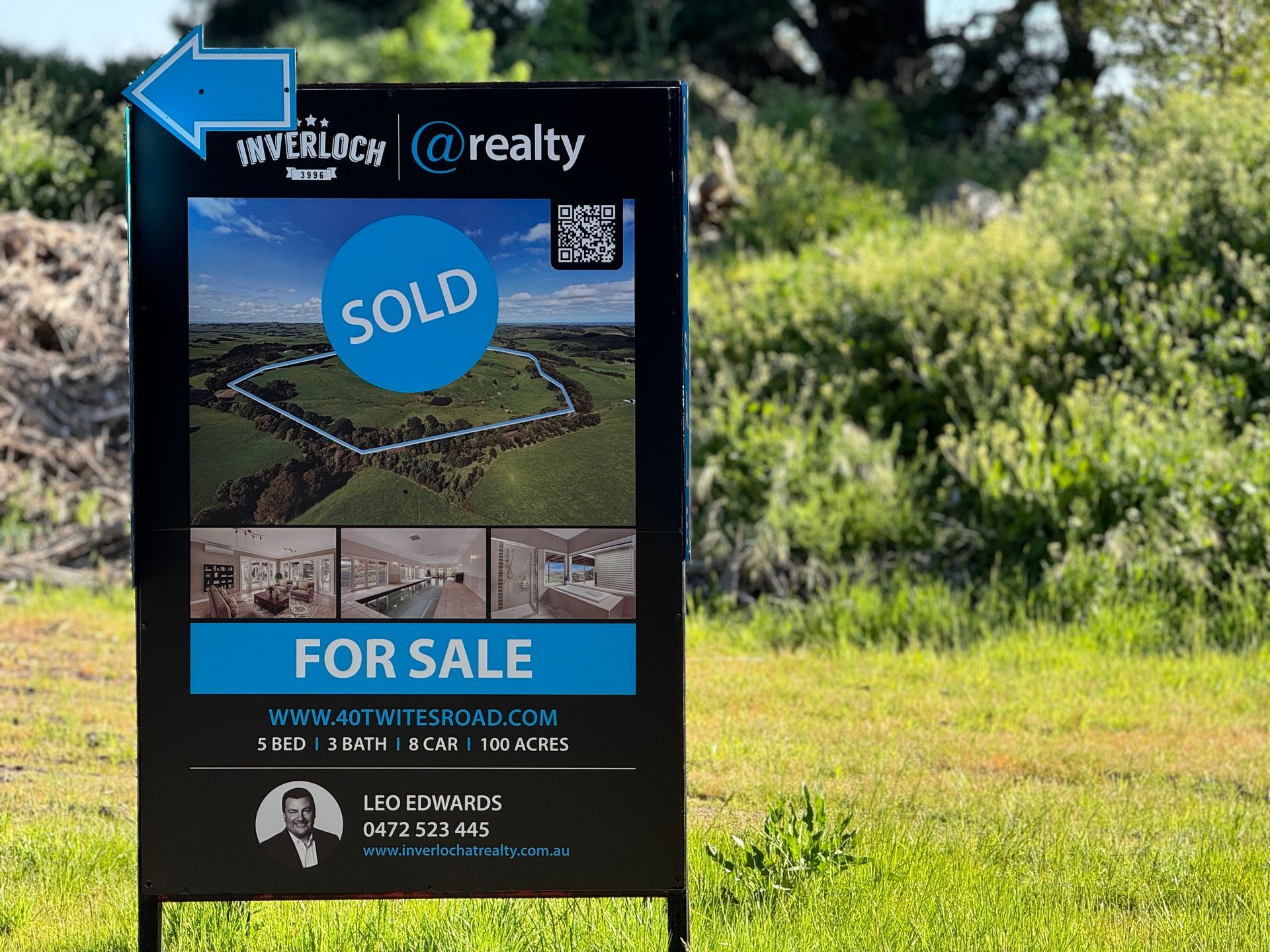 A for sale sign is sitting in the middle of a grassy field.