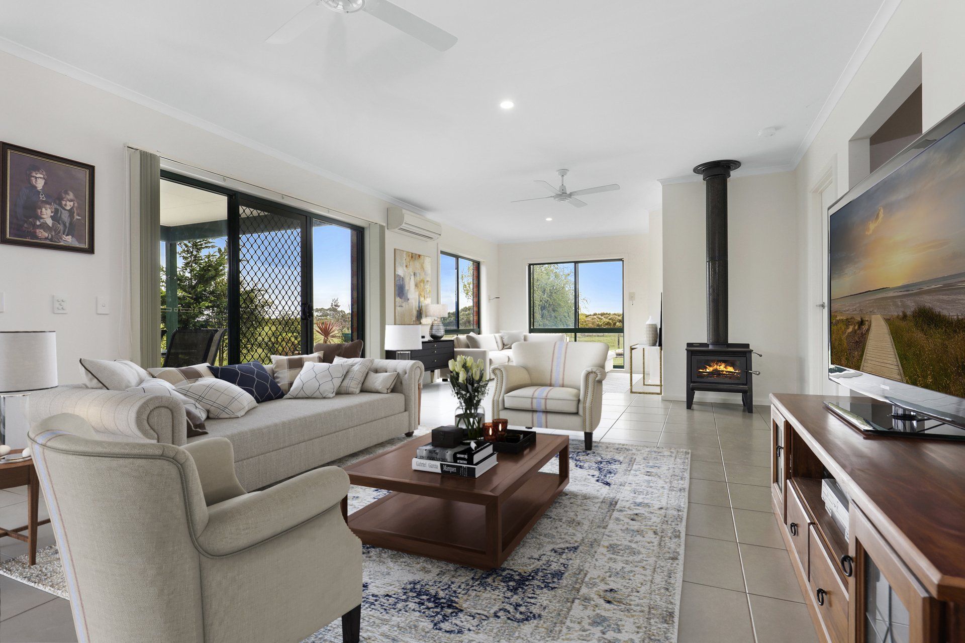 A living room with a couch , chairs , coffee table and television.