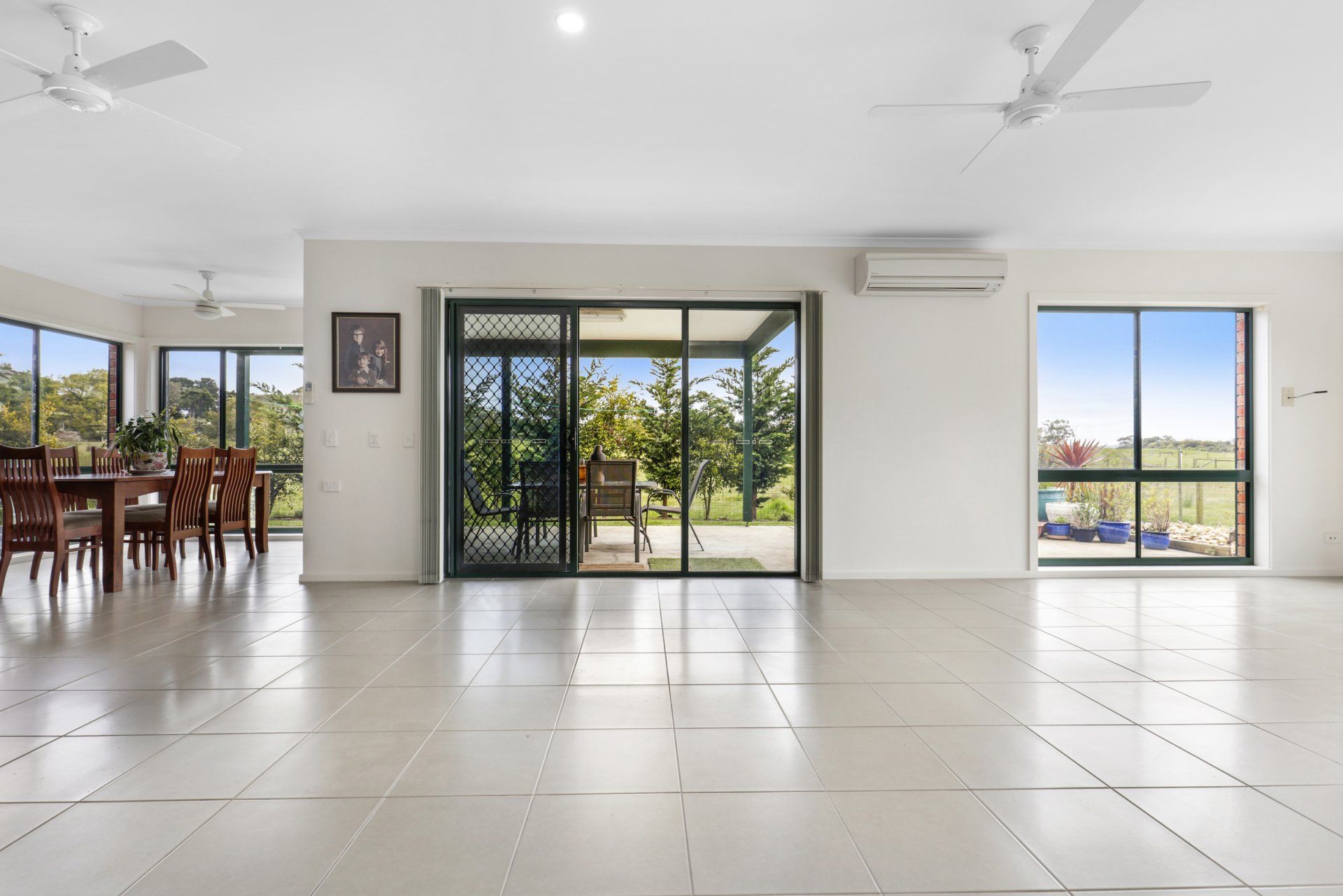 A large empty room with a ceiling fan and sliding glass doors