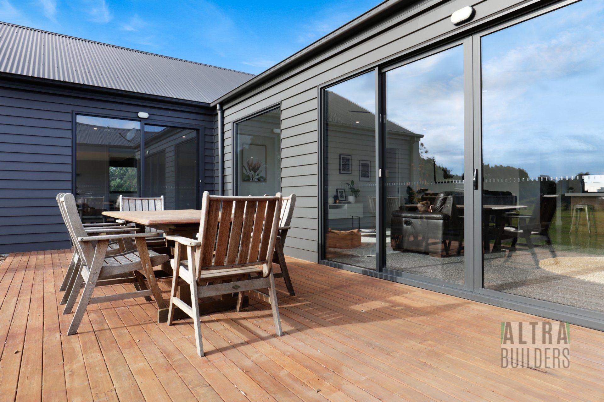 A wooden deck with a table and chairs in front of a house.