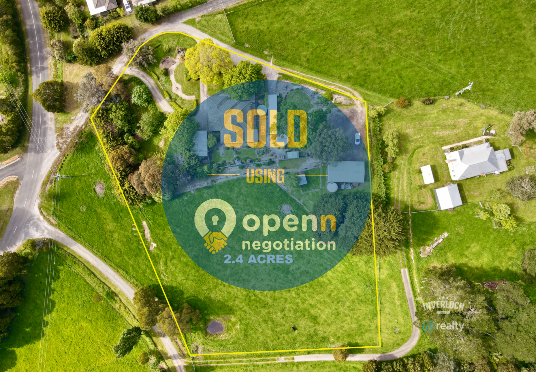 An aerial view of a lush green field with a house in the background.