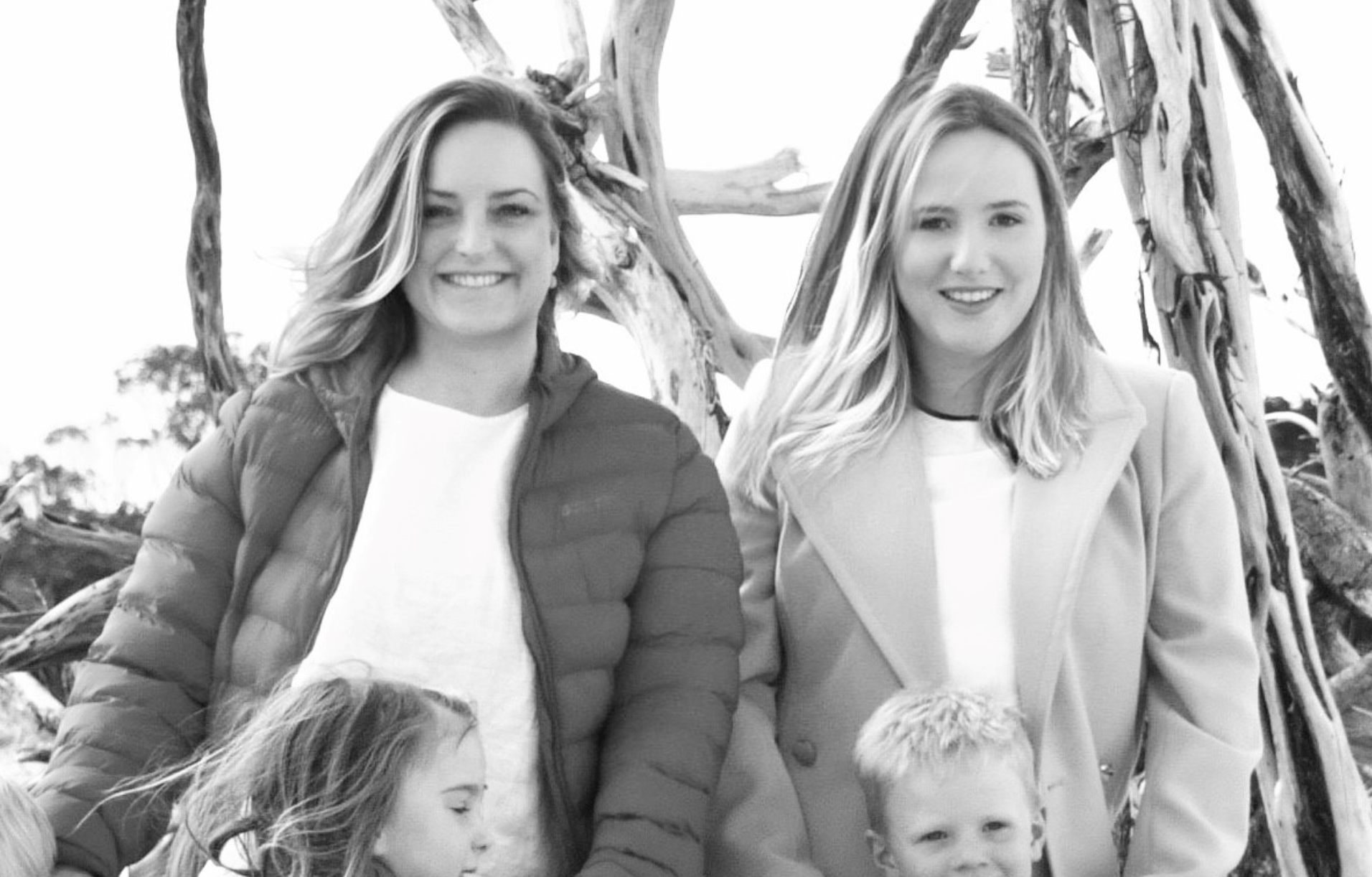 Two women and two children are posing for a picture in a black and white photo.
