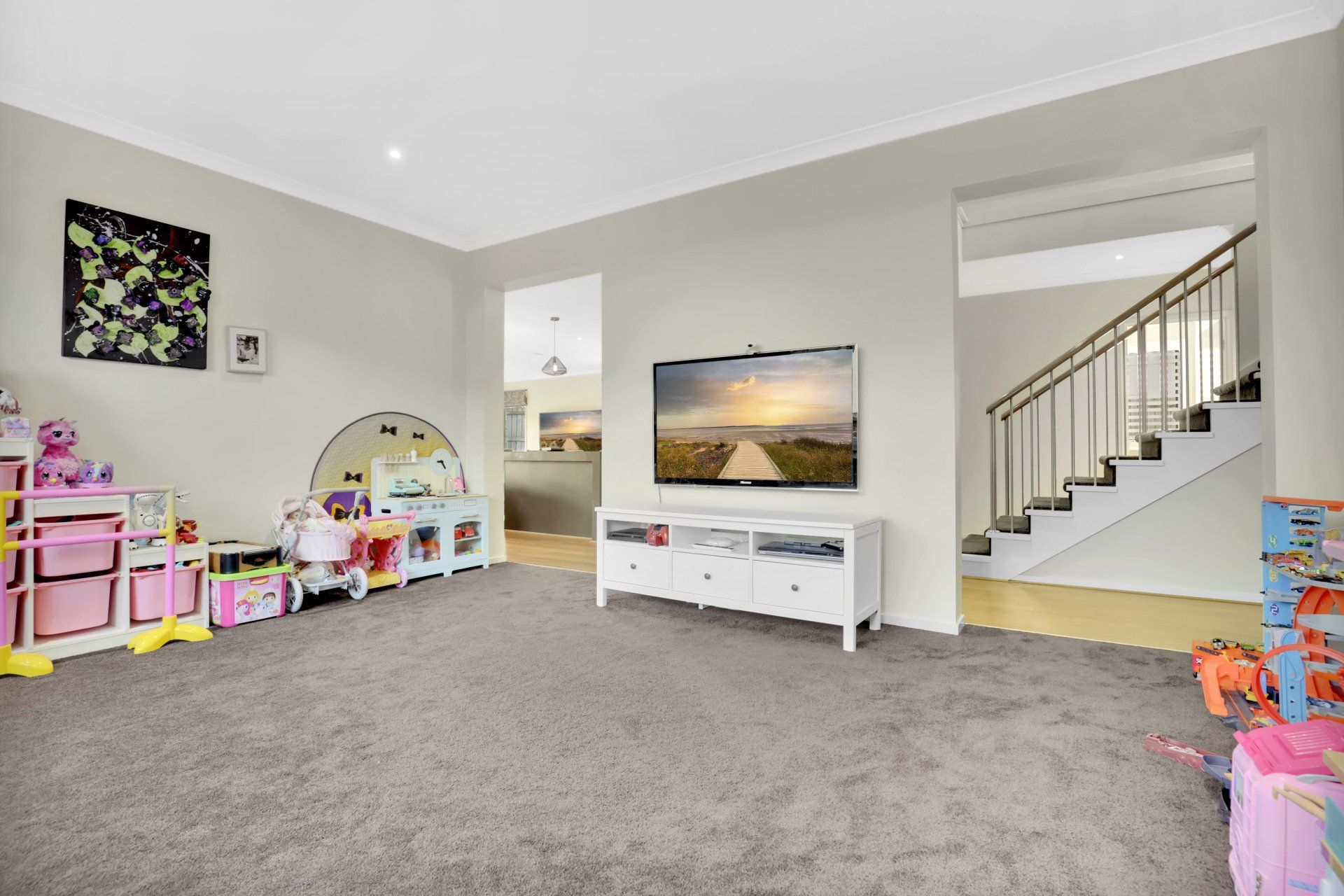 A living room filled with lots of toys and a flat screen tv.
