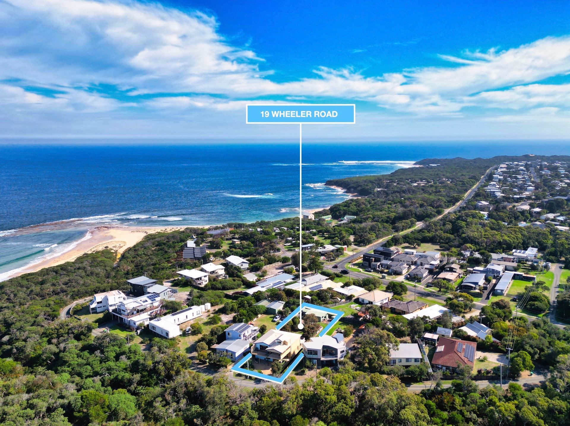 Aerial view of coastal houses near a beach and ocean under a blue sky