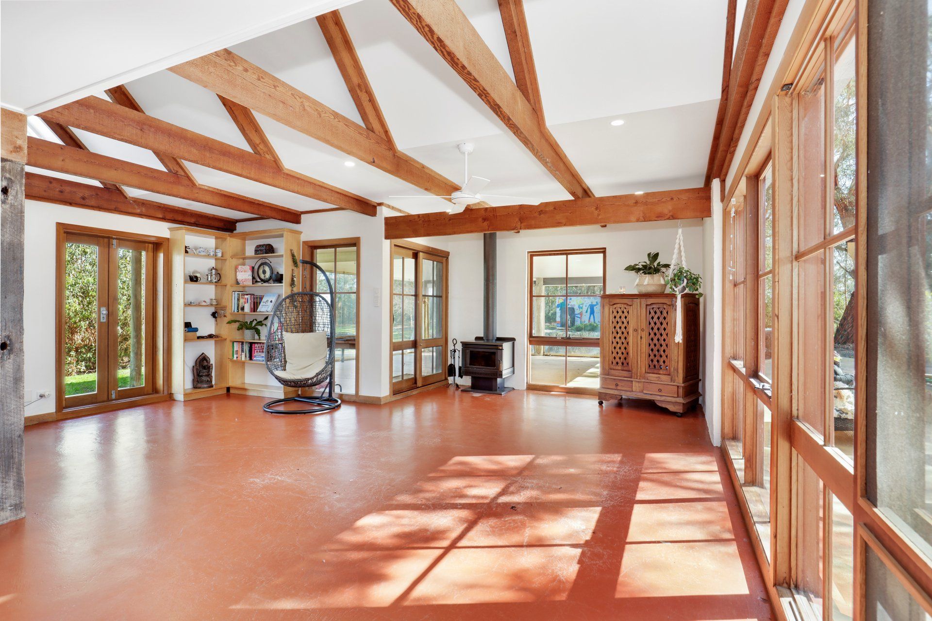 A living room with a lot of windows and wooden beams