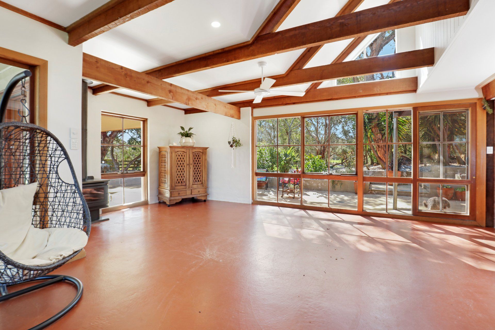 A large empty room with lots of windows and wooden beams.