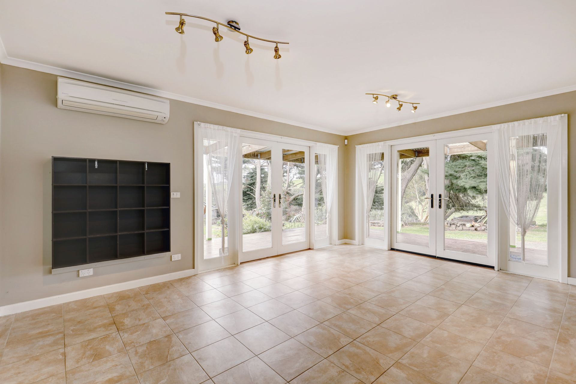 An empty living room with sliding glass doors and a flat screen tv.