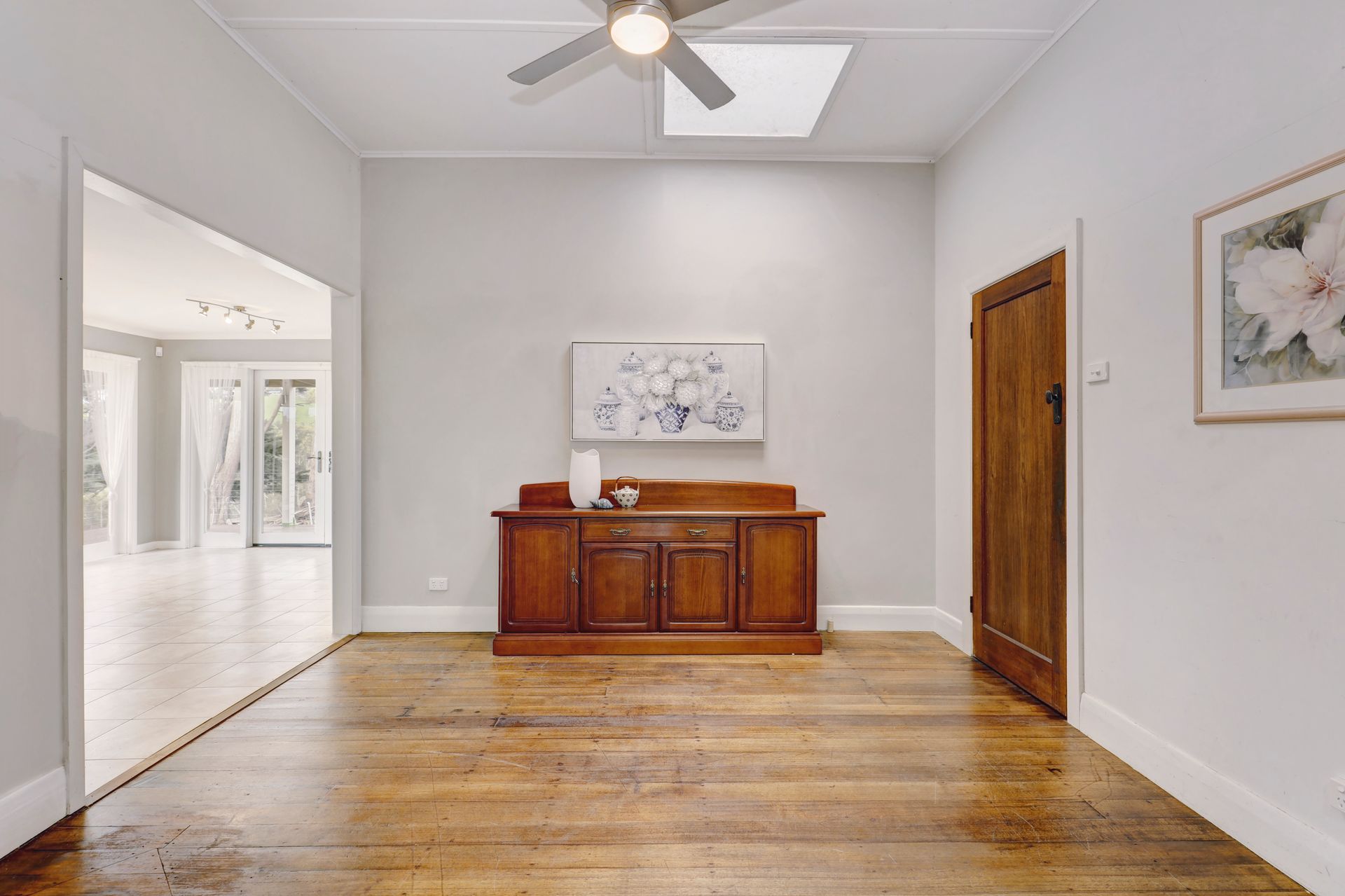 An empty room with a wooden dresser and a ceiling fan.