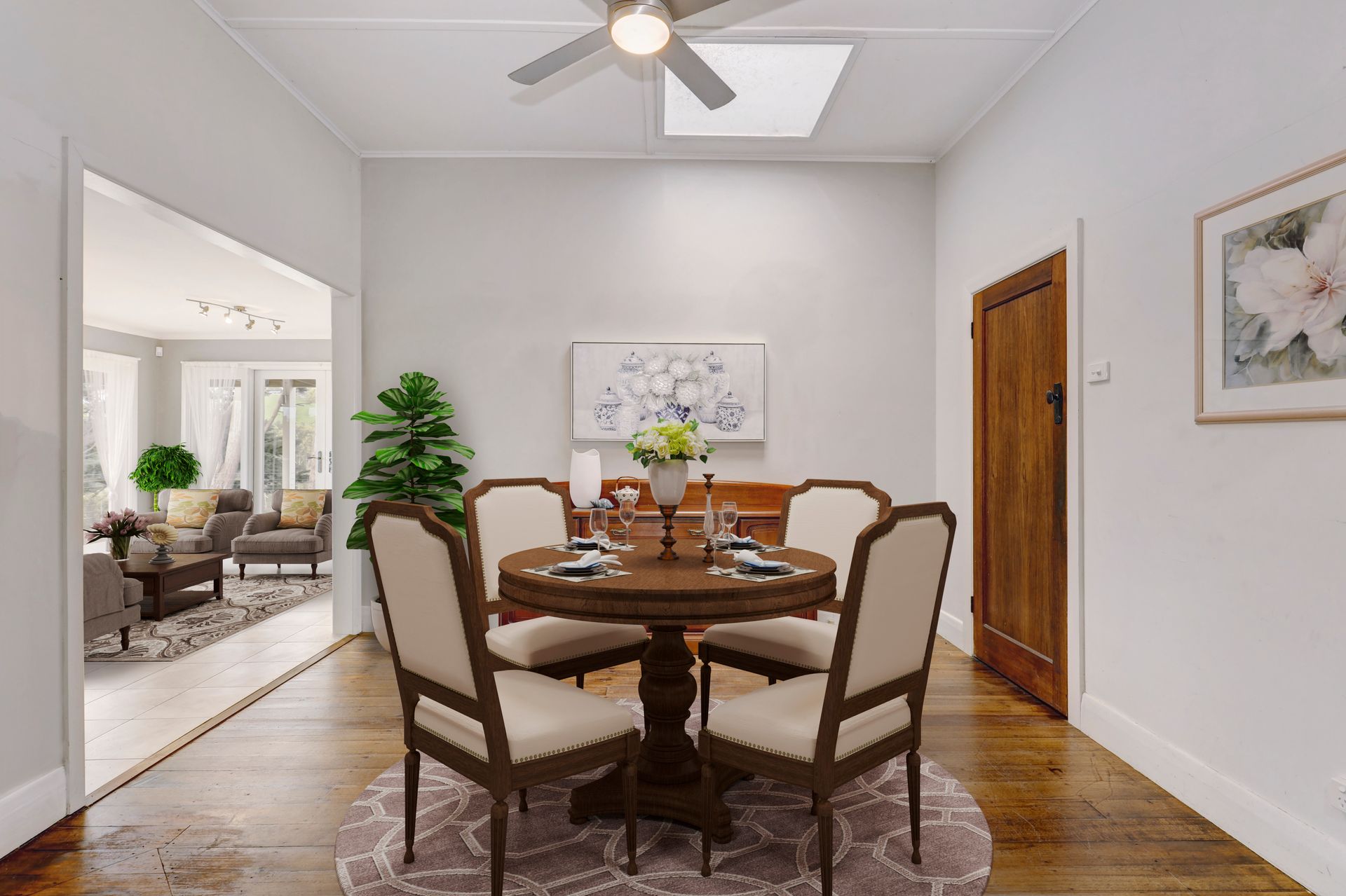 A dining room with a round table and chairs and a ceiling fan.