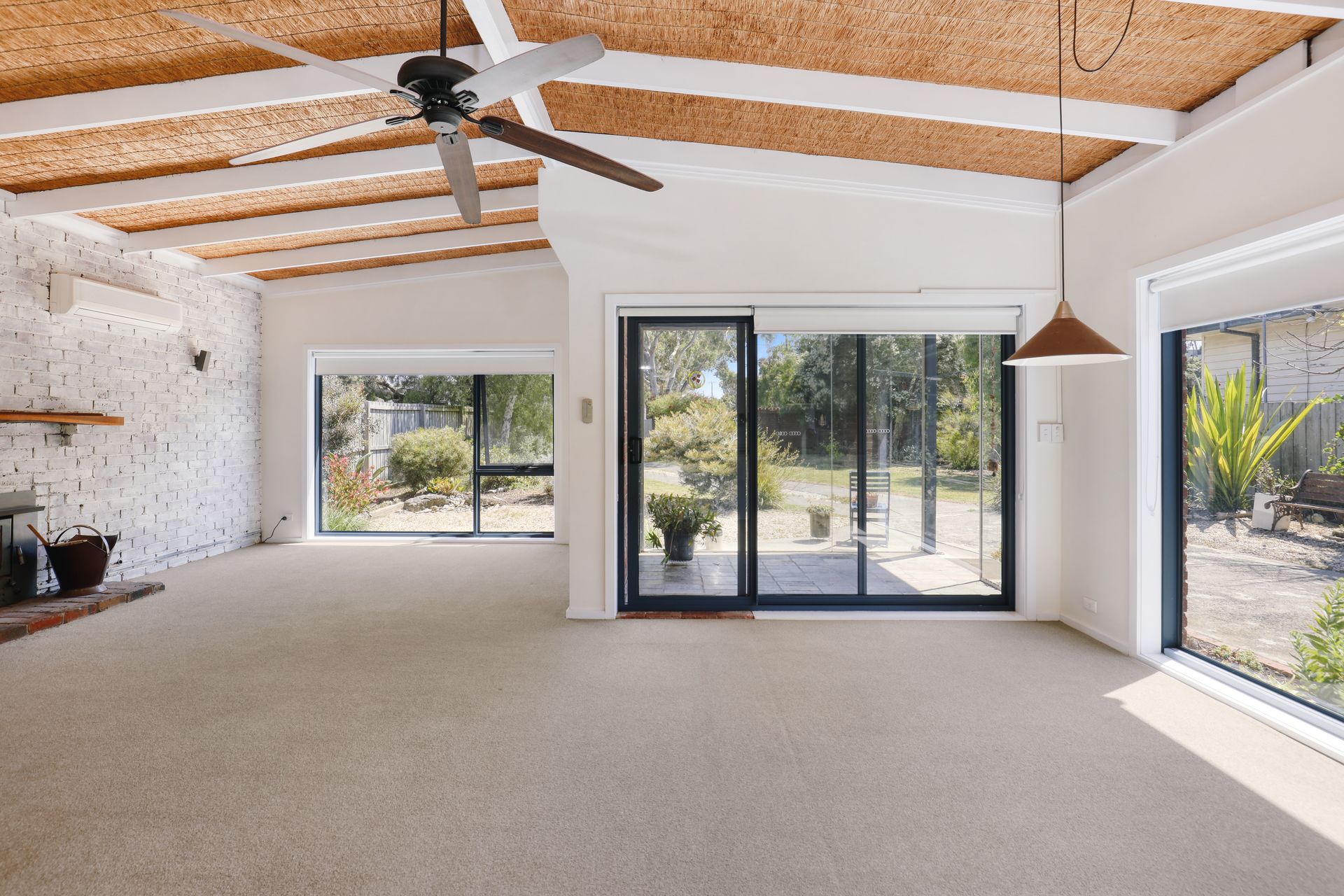 An empty living room with a ceiling fan and sliding glass doors.