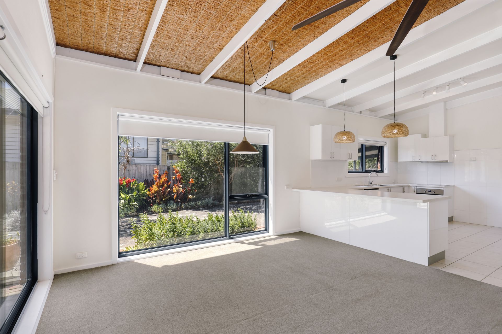 An empty room with a ceiling fan and a large window.