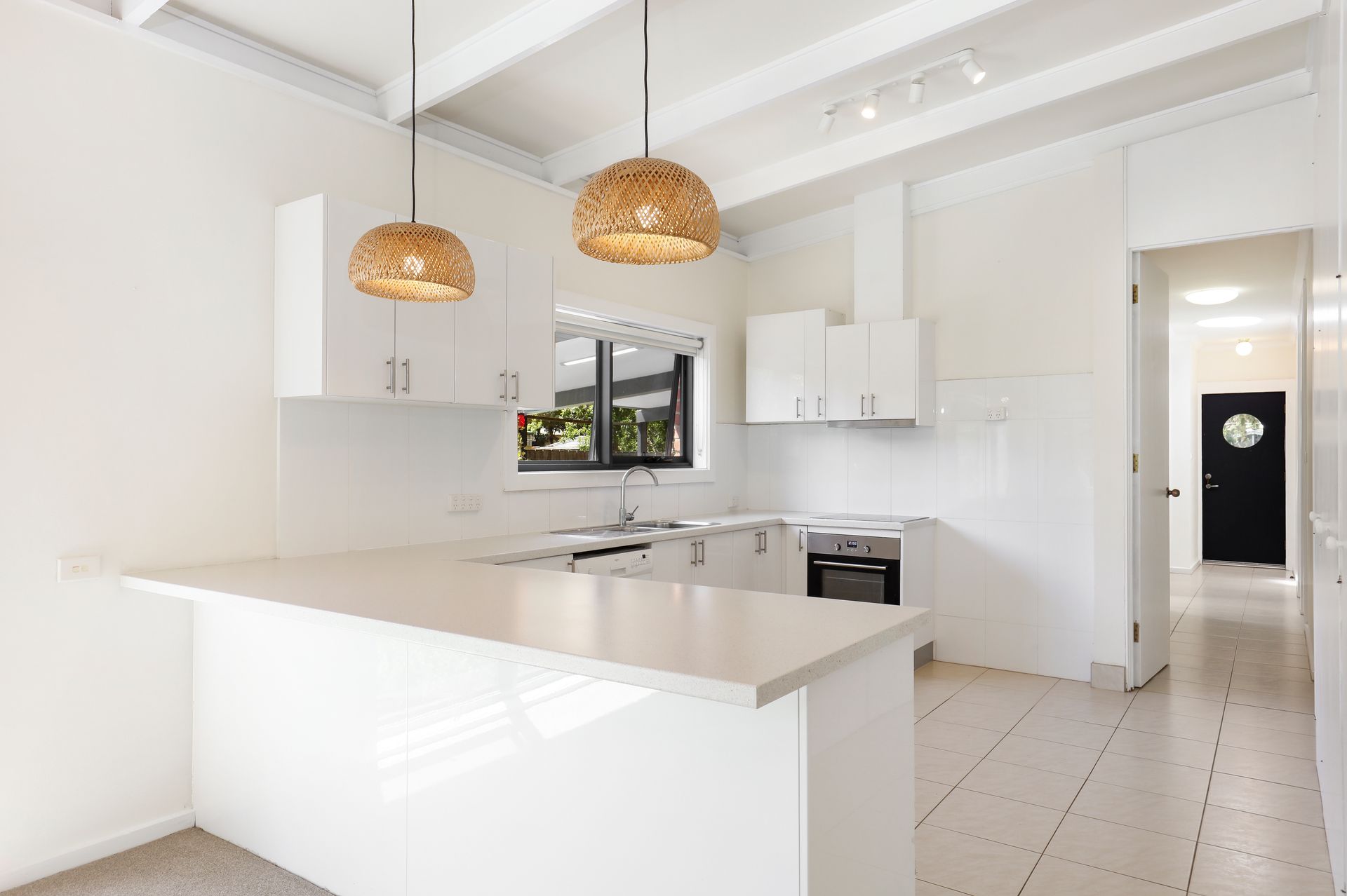 An empty kitchen with white cabinets and a large island.