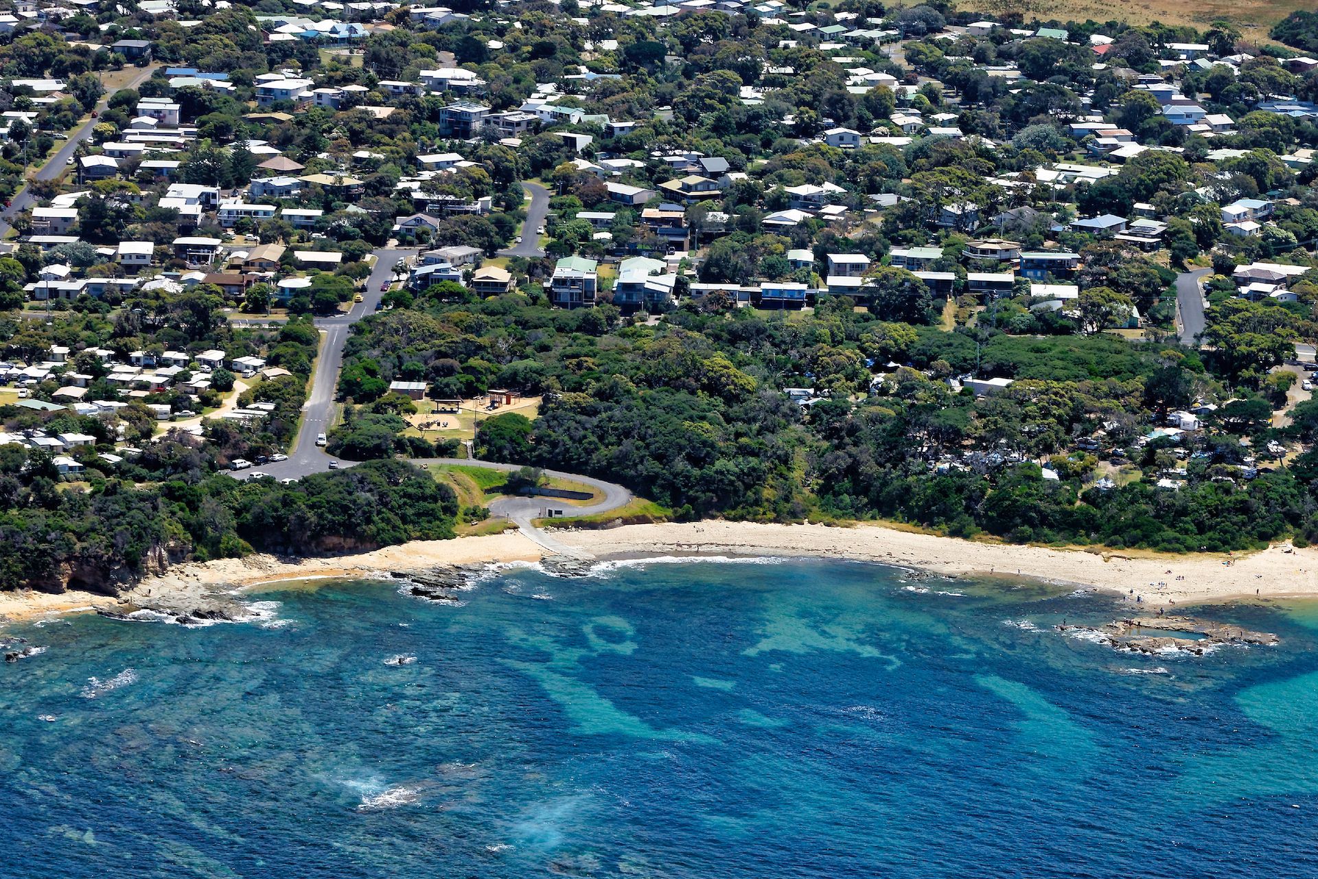 Aerial view of a coastal neighborhood with a sandy beach and blue ocean shoreline