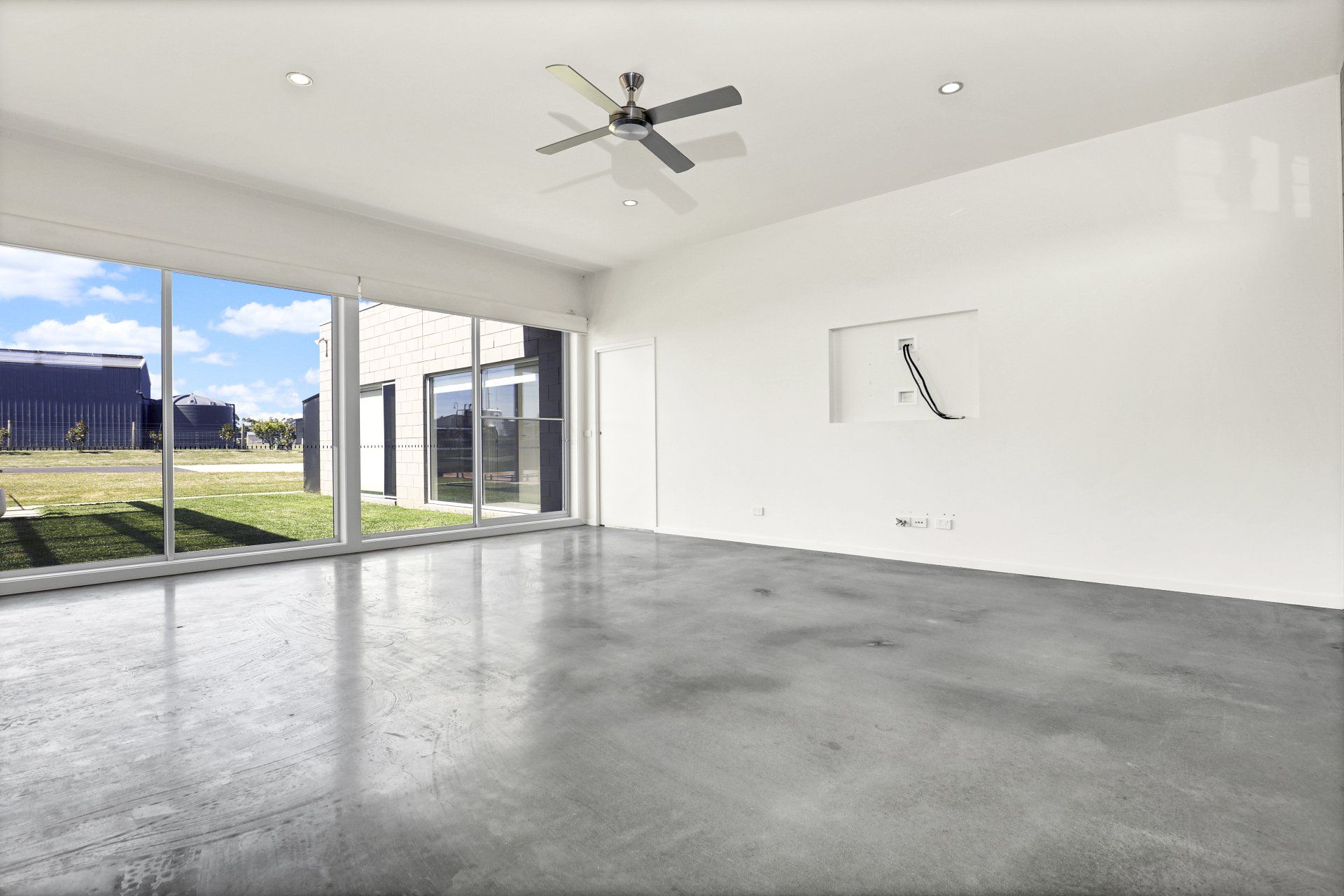 An empty room with a ceiling fan and a lot of windows