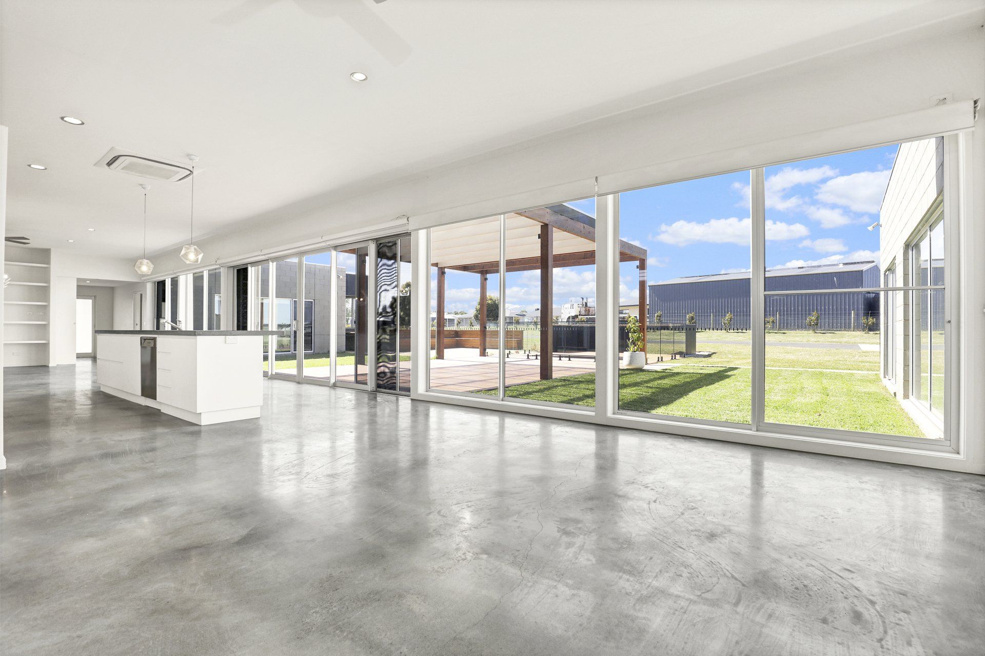 A large empty room with a lot of windows and a concrete floor.