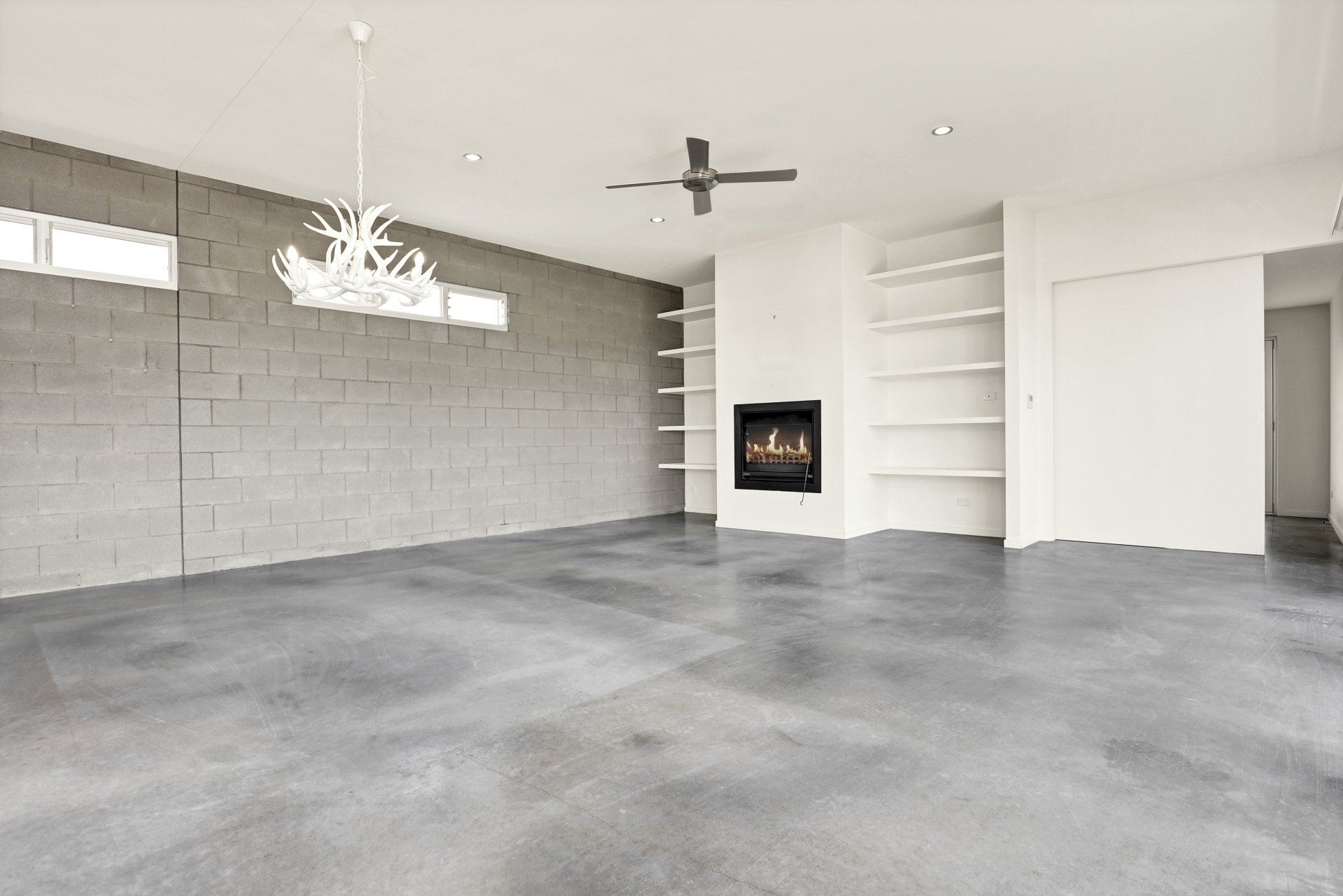 An empty living room with a fireplace and a ceiling fan.