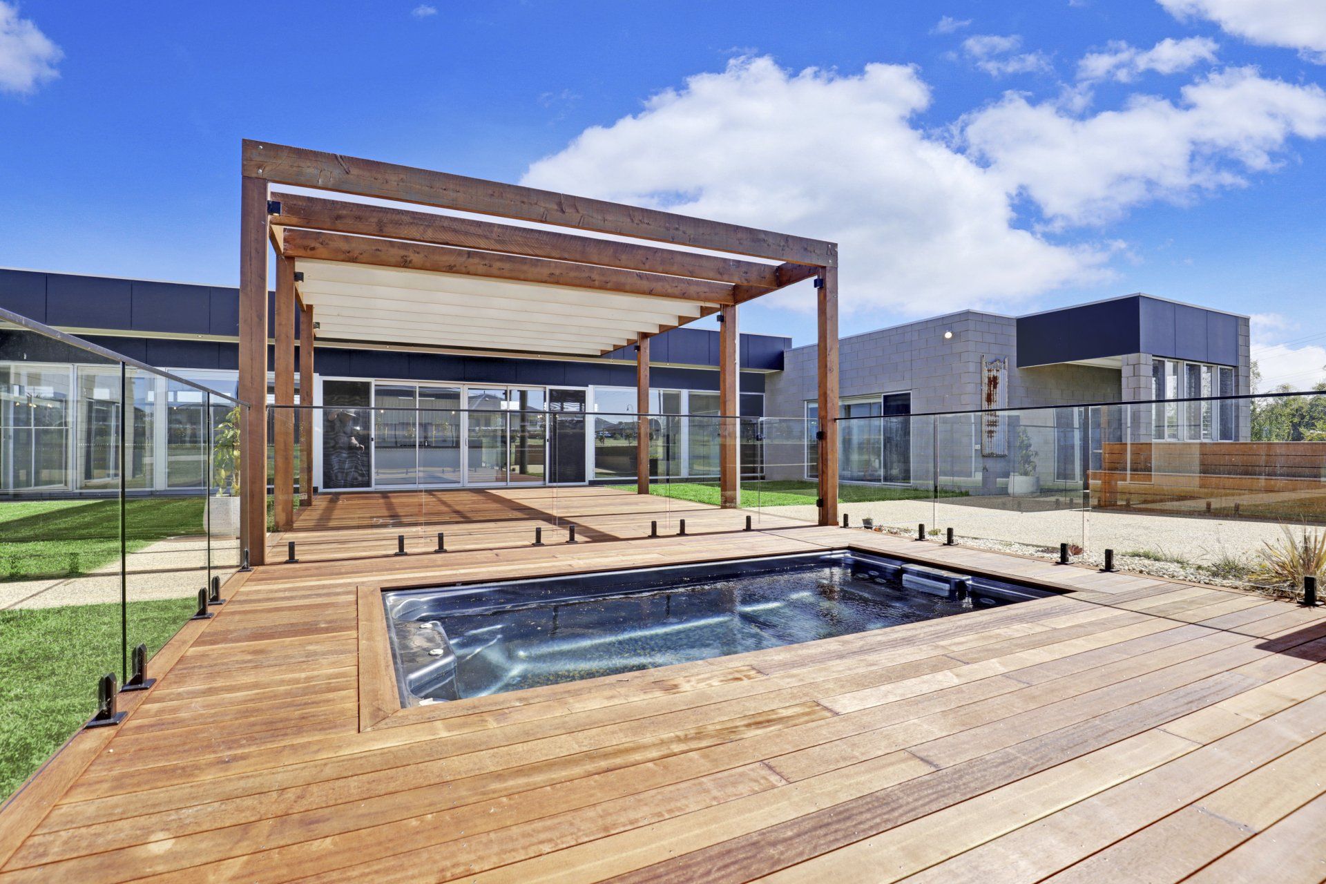 A large house with a wooden deck and a swimming pool in front of it.