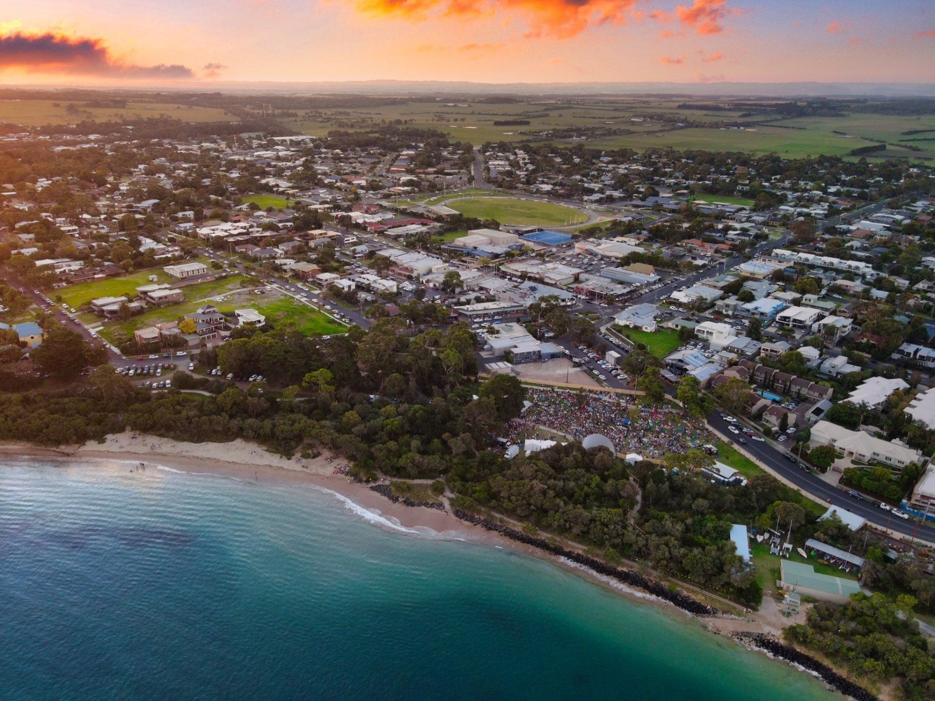 An aerial view of a city next to a body of water at sunset.