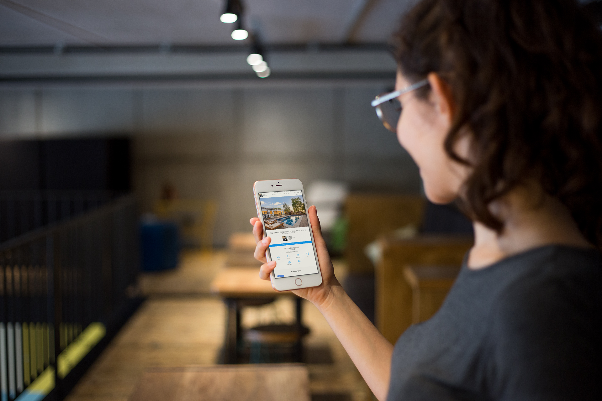 Person holding a smartphone in a dim indoor hallway, viewing a map on the screen