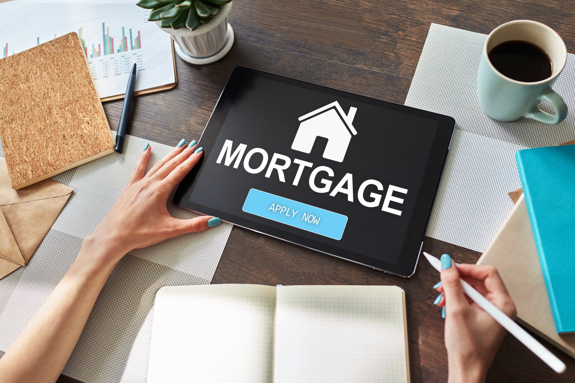 Hands reviewing a mortgage document on a desk with a tablet and coffee cup